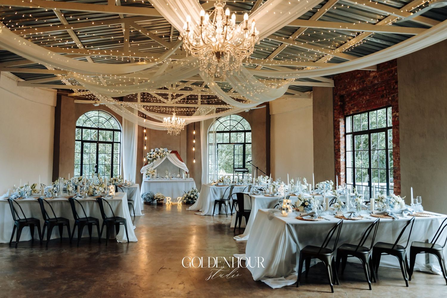 Elegant wedding reception venue with crystal chandeliers and white table settings in a spacious ballroom.