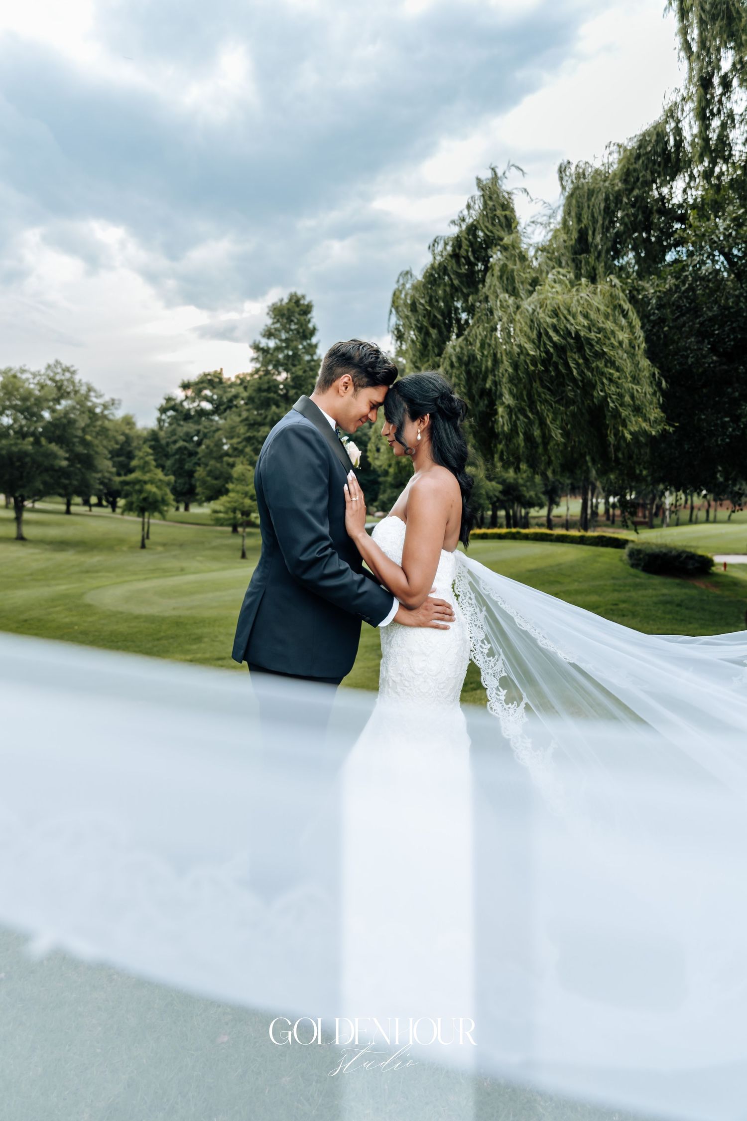 Romantic wedding couple portraits on golf course with flowing veil.