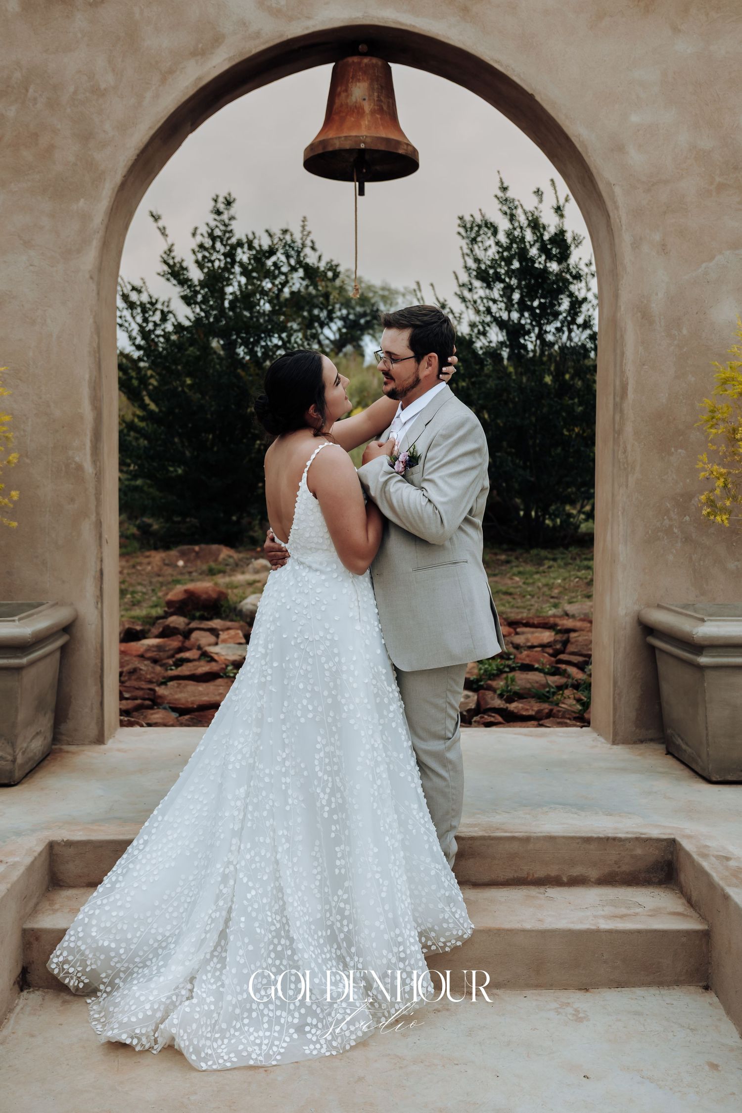 Couple shares a dance moment under stone archways during wedding celebration.