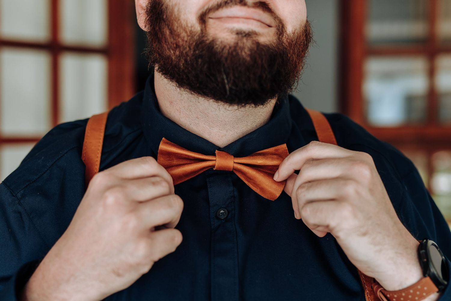 Close-up sequence showing hands adjusting an orange bow tie against a dark suit.