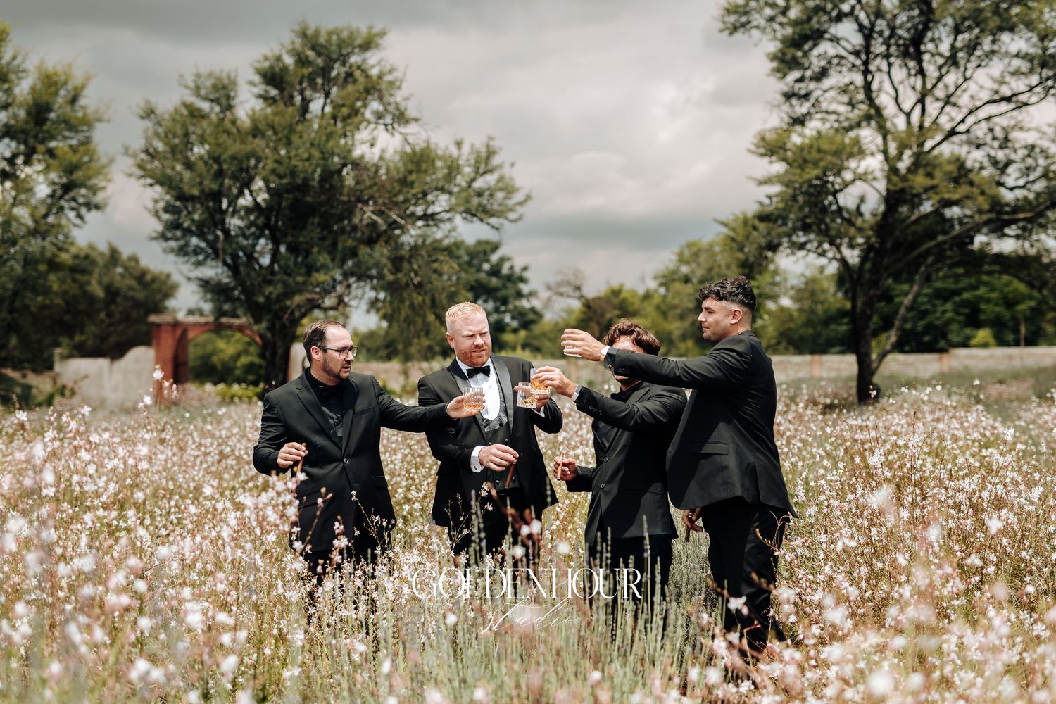 Wedding party laughs together while standing in a scenic cotton field on an overcast day.