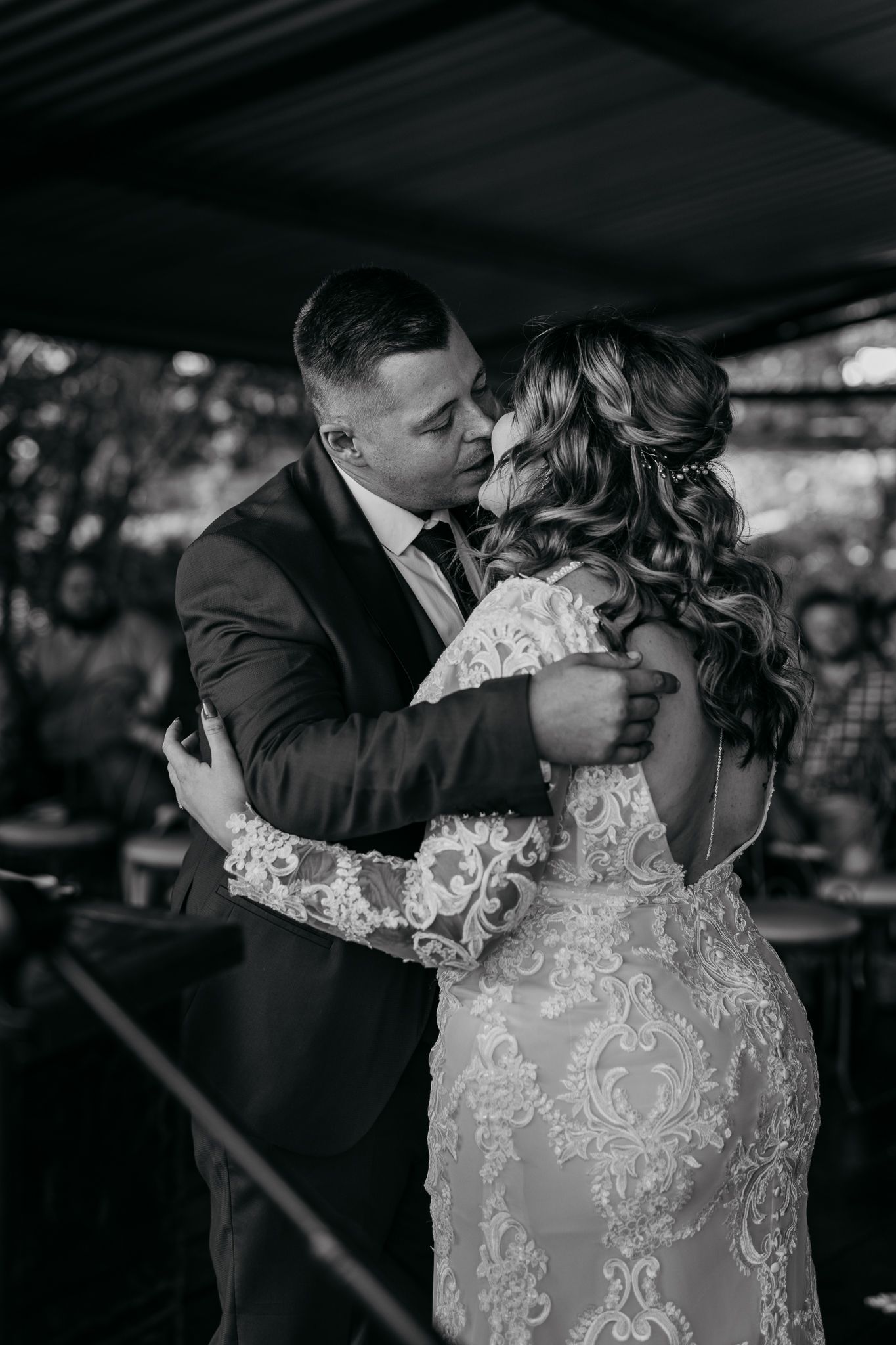 Couple shares an intimate moment during their first dance at wedding reception in black and white photography.