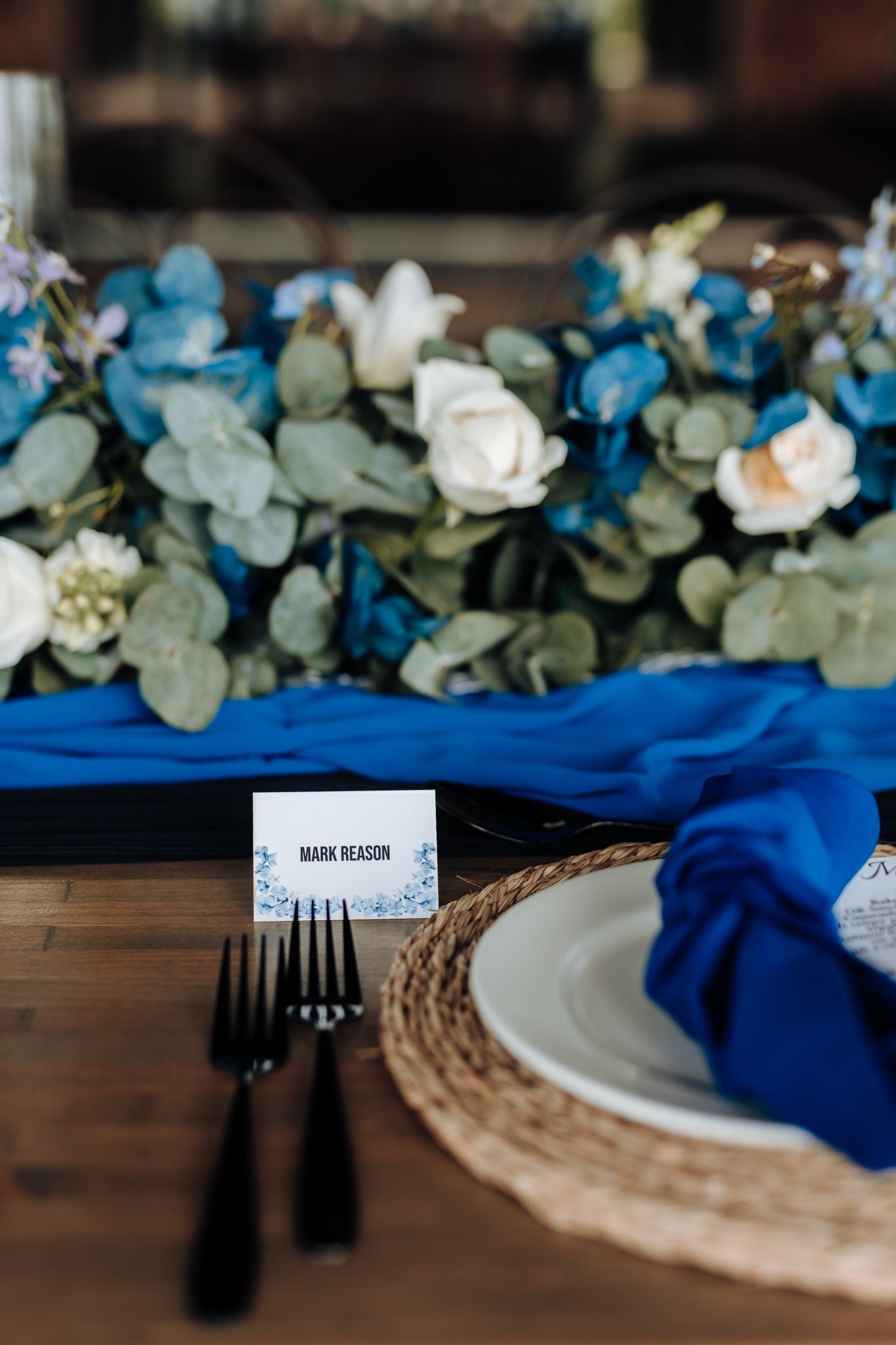 Place setting with blue and white floral arrangements and gold charger plate.