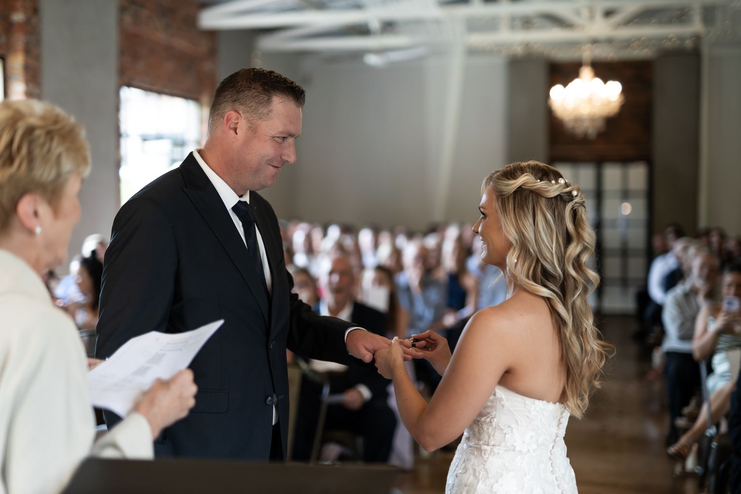 A couple exchanges wedding vows in front of gathered guests during their ceremony.