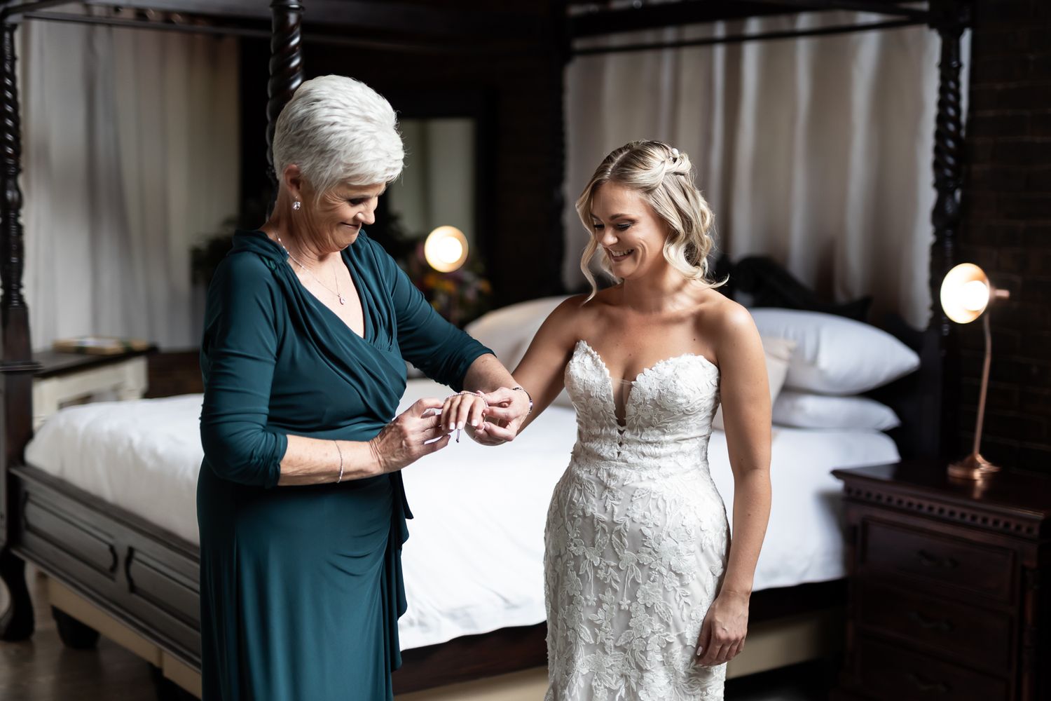 Two women helping with wedding preparations in a beautifully decorated bedroom.