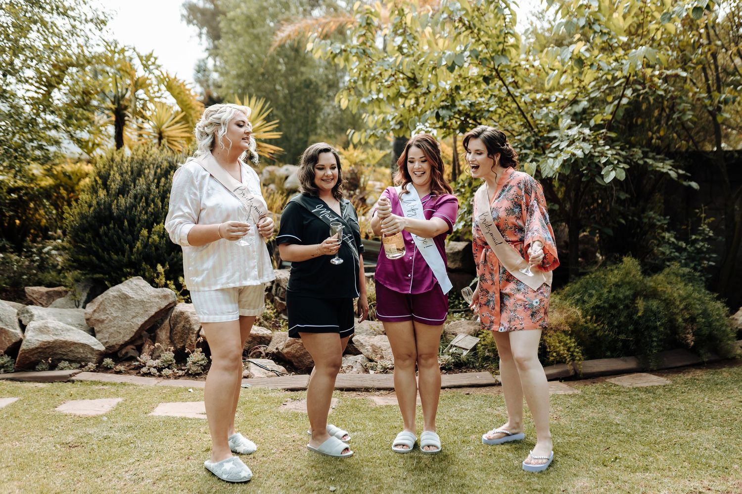 A group celebrates in a garden setting wearing casual attire and sneakers during a pre-wedding gathering.