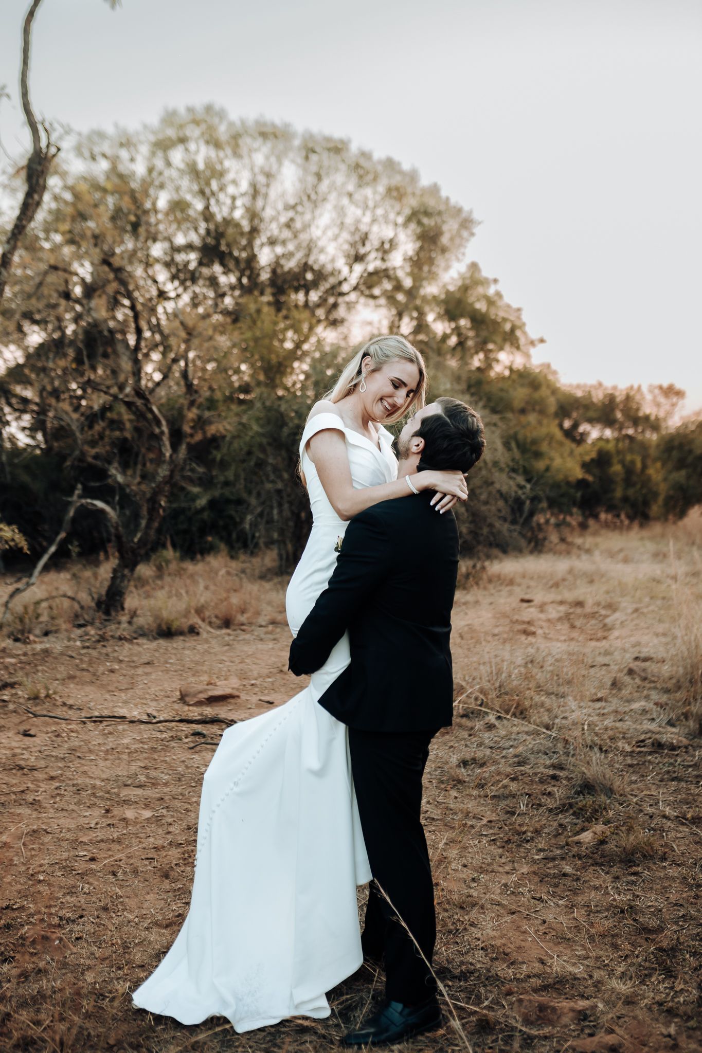 A couple shares a romantic dance pose on a rustic outdoor trail.