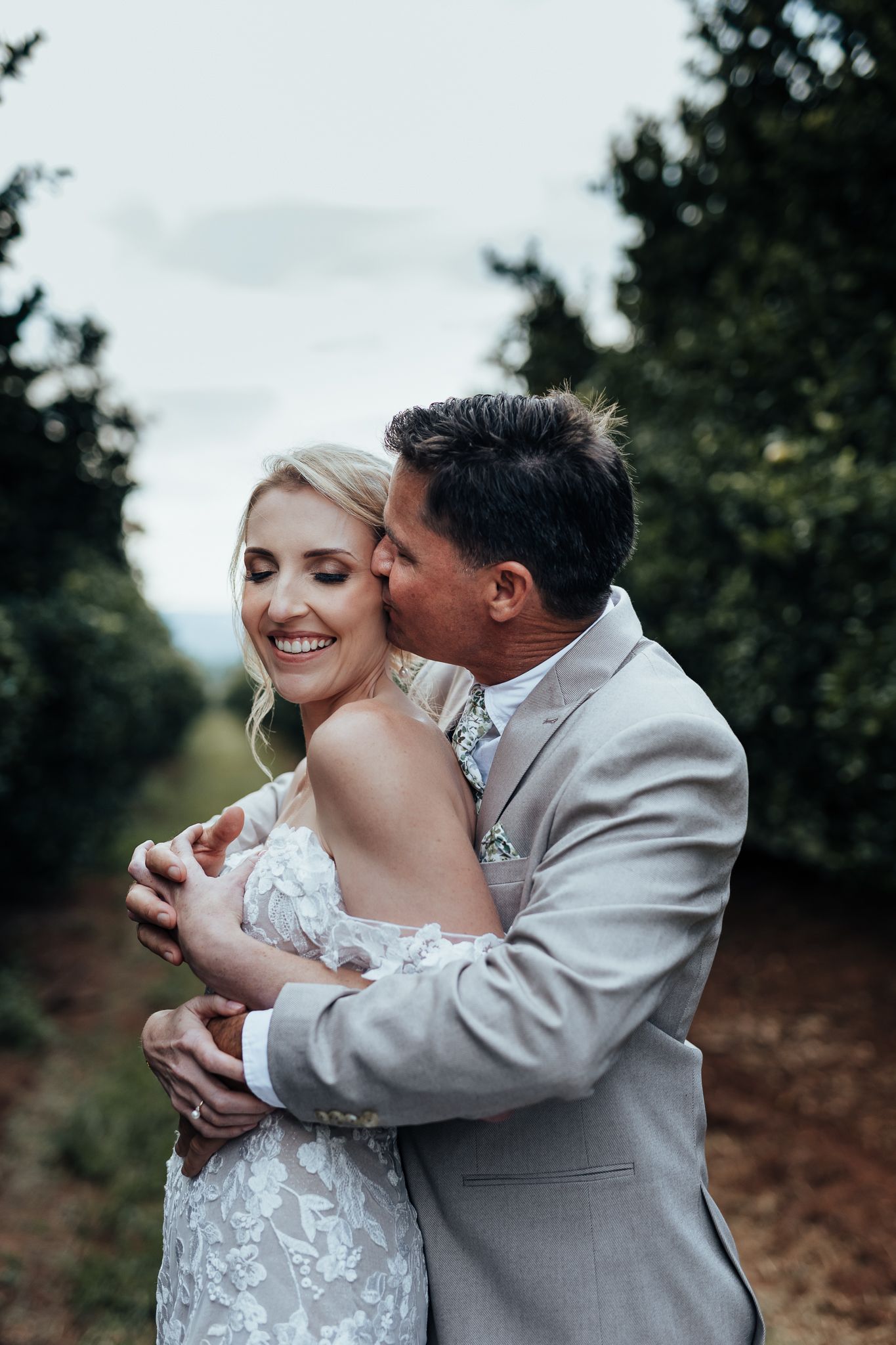 A romantic wedding photo of a couple embracing in a garden setting with soft natural lighting.