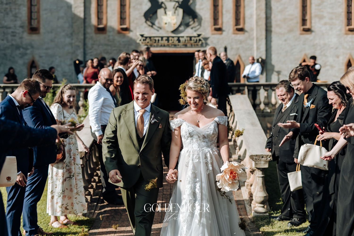 Bride and groom walk joyfully down the aisle outdoors after wedding ceremony with guests cheering.