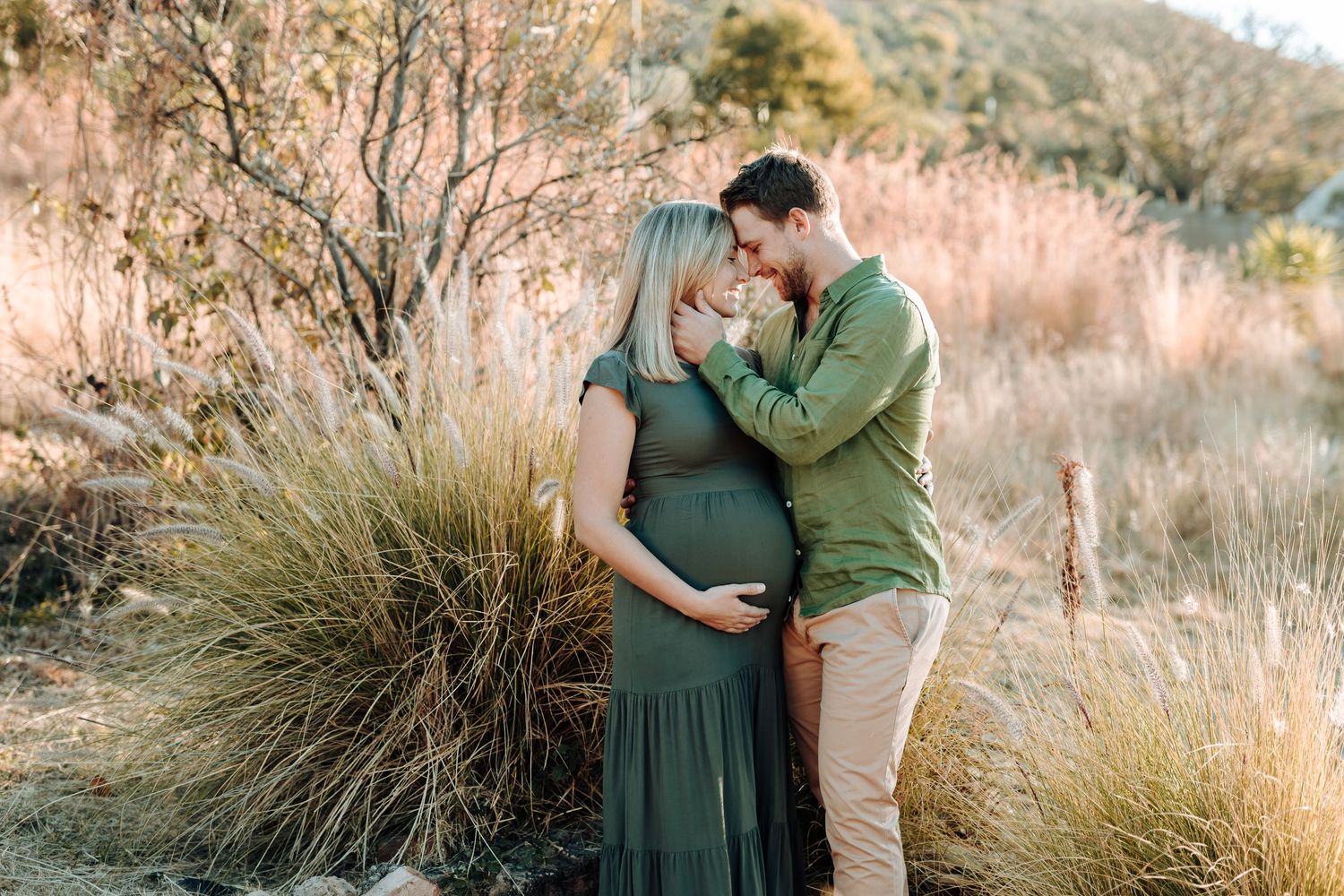 Intimate family moment captured at sunset in rustic desert landscape surrounded by native grasses and trees.