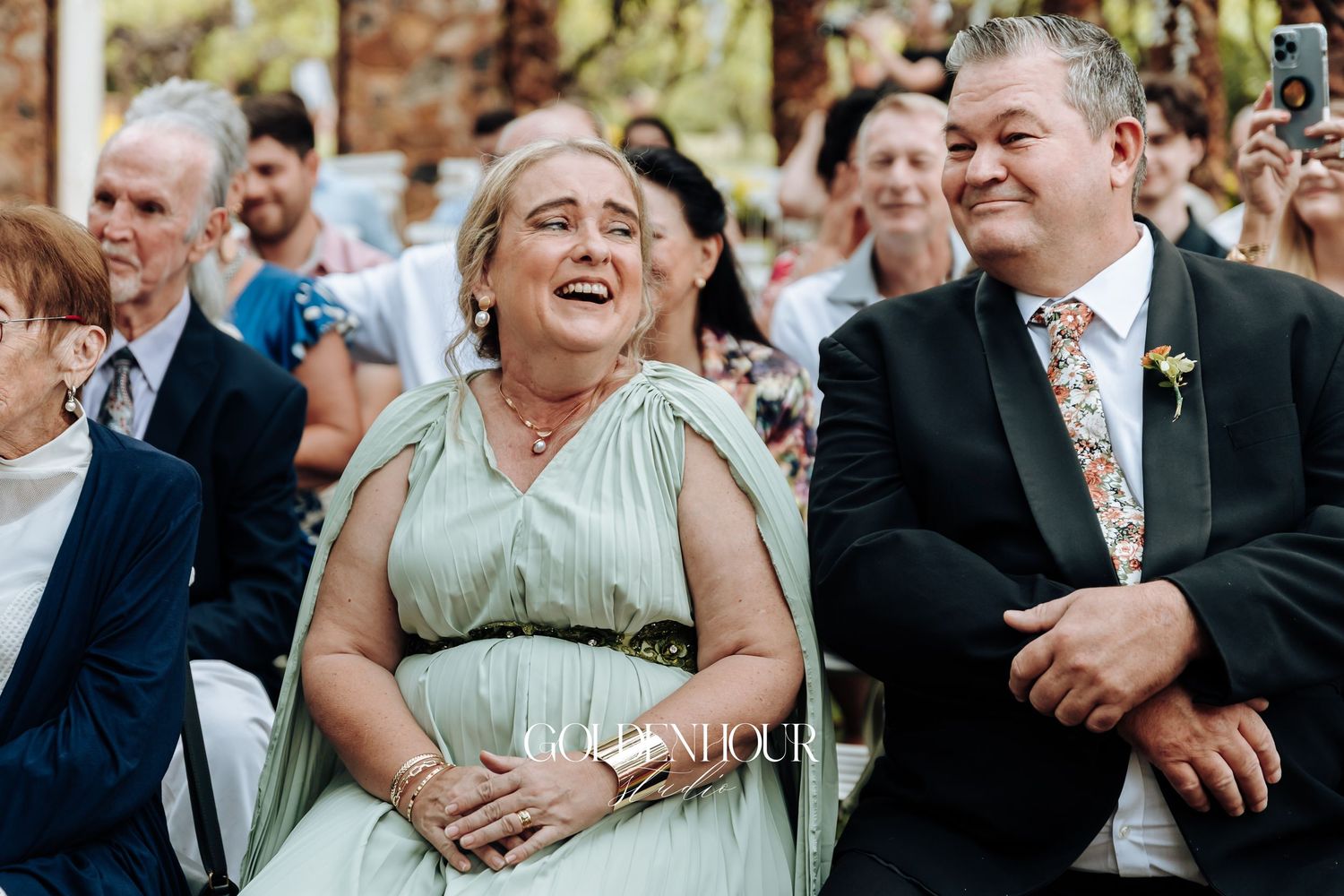 Wedding guests laughing and enjoying themselves during outdoor celebration.