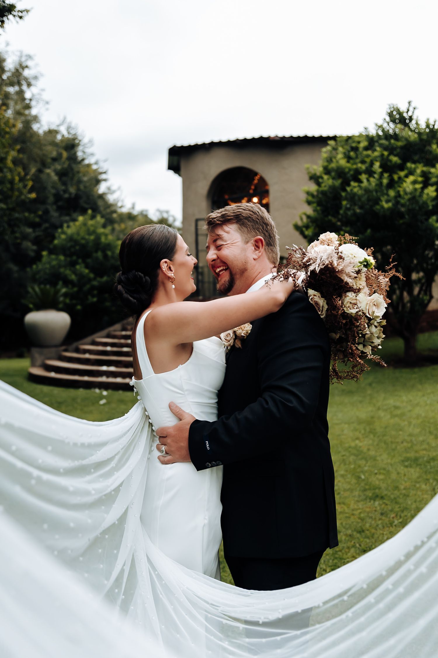 Romantic wedding couple dancing and twirling in garden with flowing white dress train creating elegant movement.