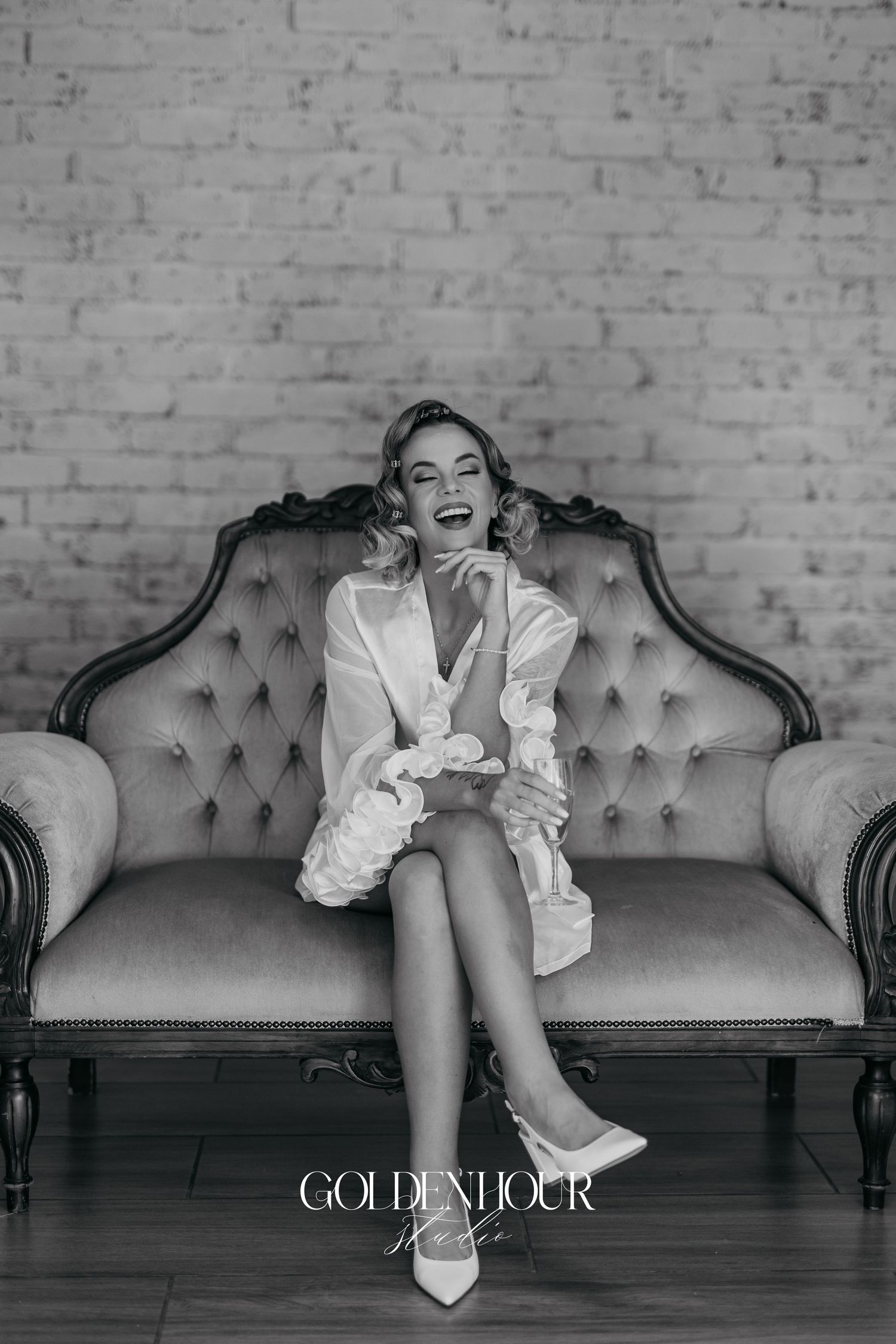 Artistic black and white photo of white boots and ruffled dress details on a vintage tufted sofa.