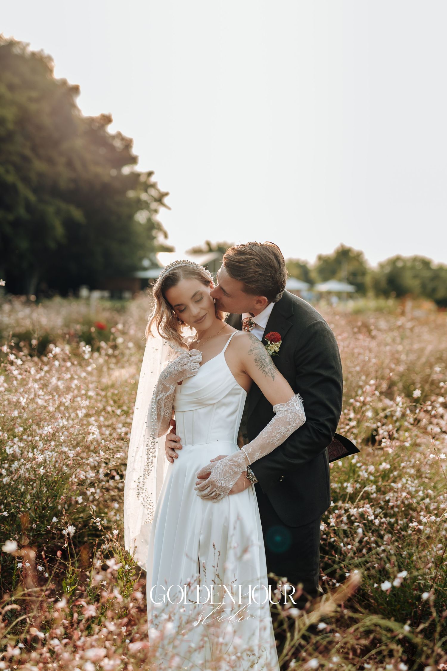 Romantic couple portrait in flowering field during golden hour wedding photography session.