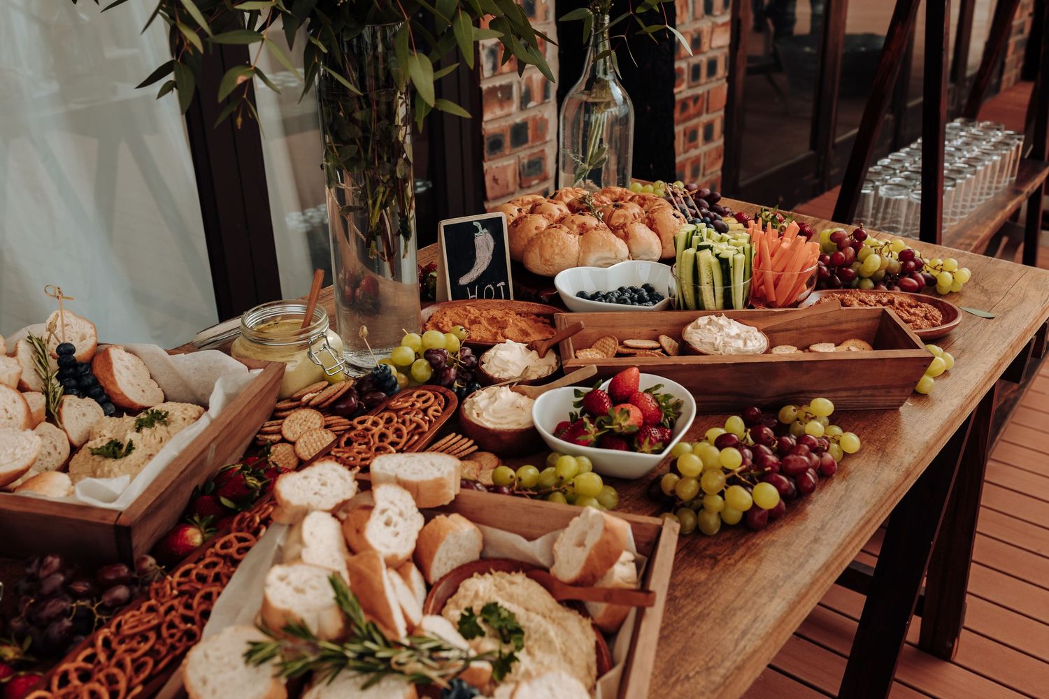 A rustic wooden table filled with charcuterie, fresh bread, fruits, meats, cheeses and appetizers for entertaining.