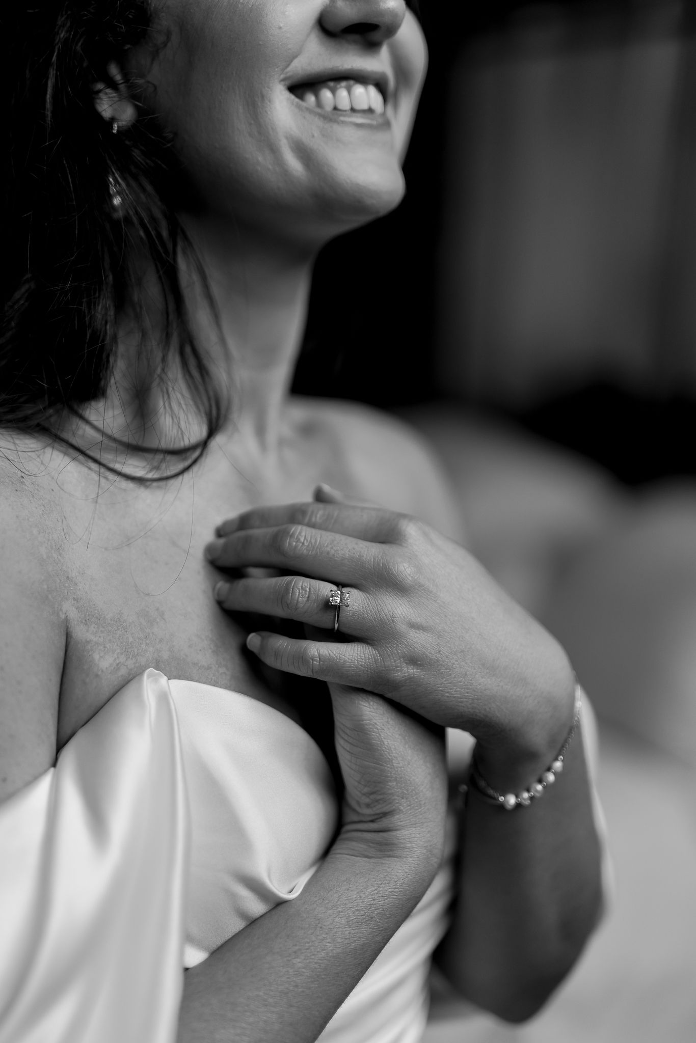 Black and white close-up of wedding ring and bracelet detail on bride's hand.