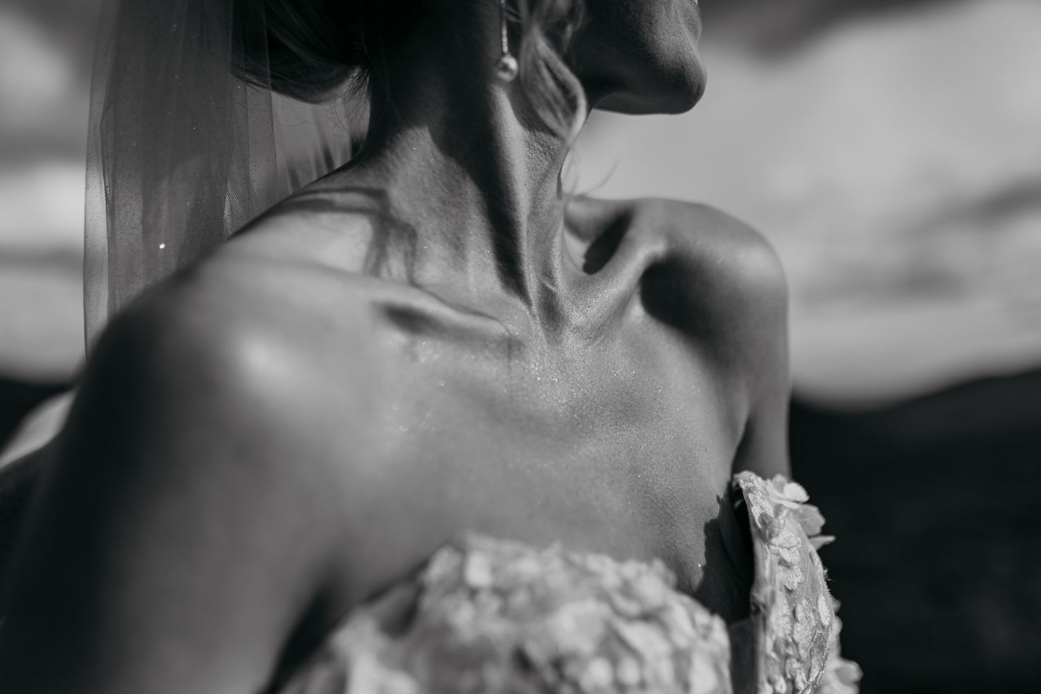 Close-up black and white shot showing neck and shoulder detail of bride wearing strapless wedding dress.