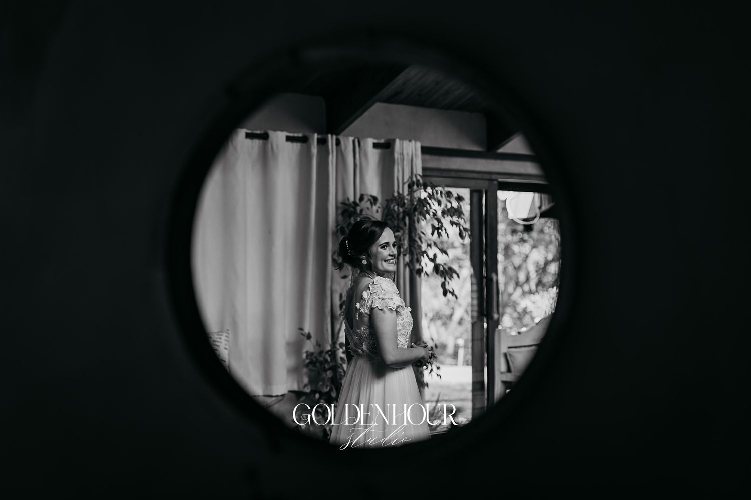 Bride reflected in round mirror in black and white wedding photo.