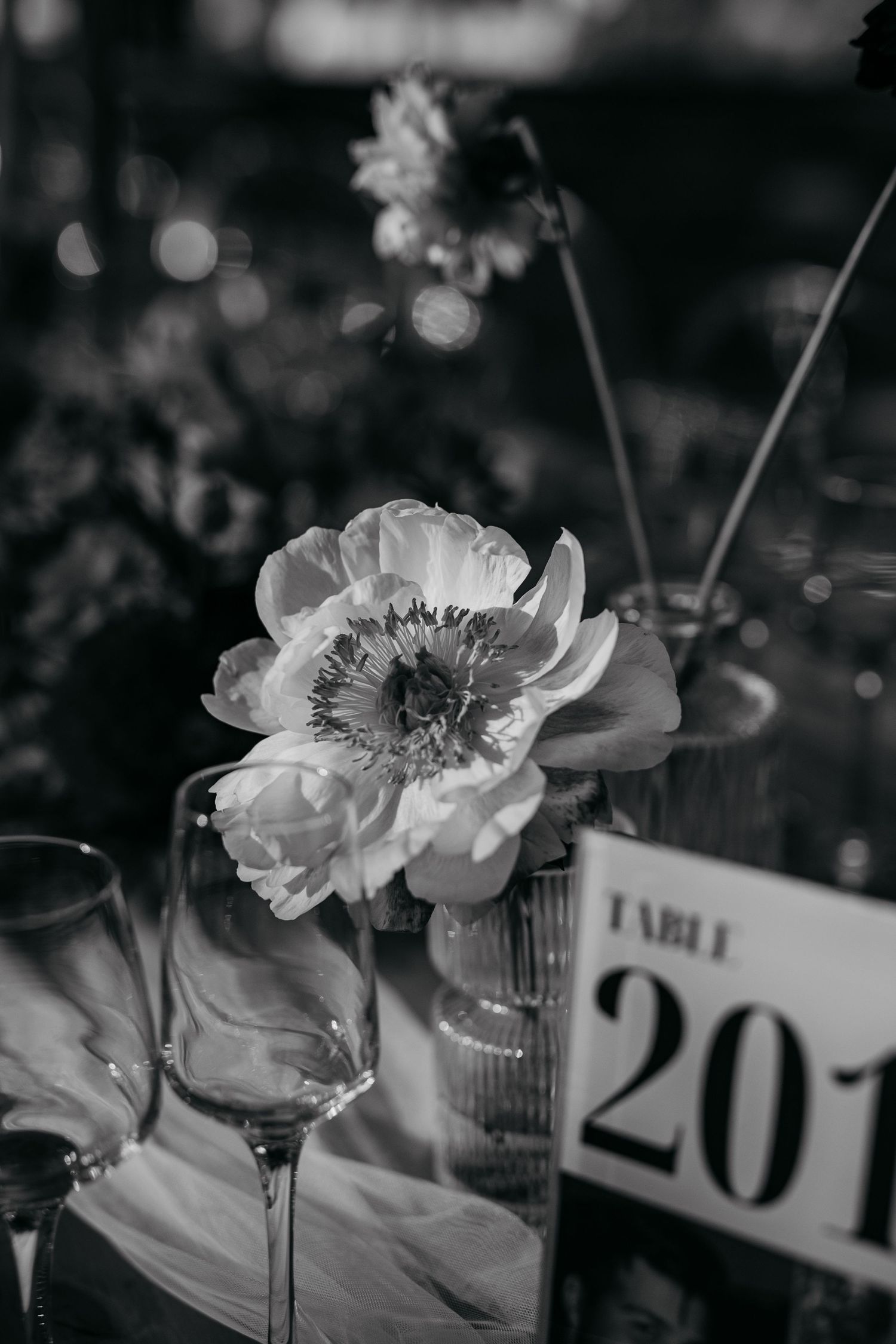 Black and white floral centerpiece arrangements with table numbers at an elegant wedding reception.