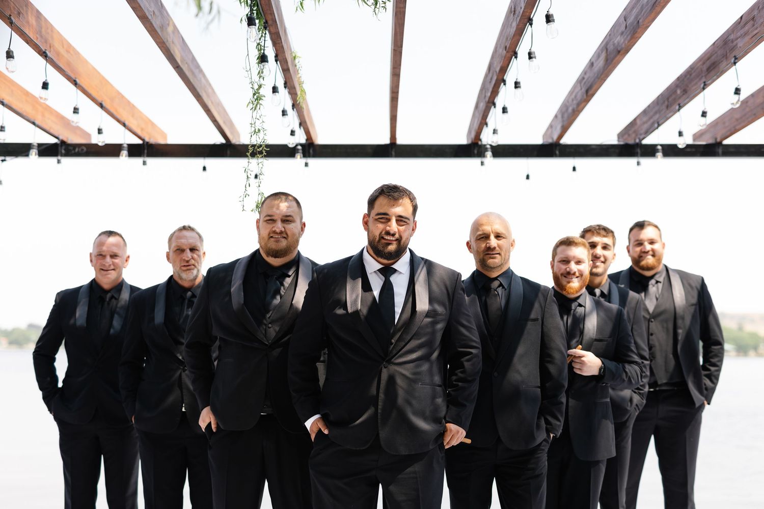 Group of men in black suits and formal attire posing together for a formal event photo.