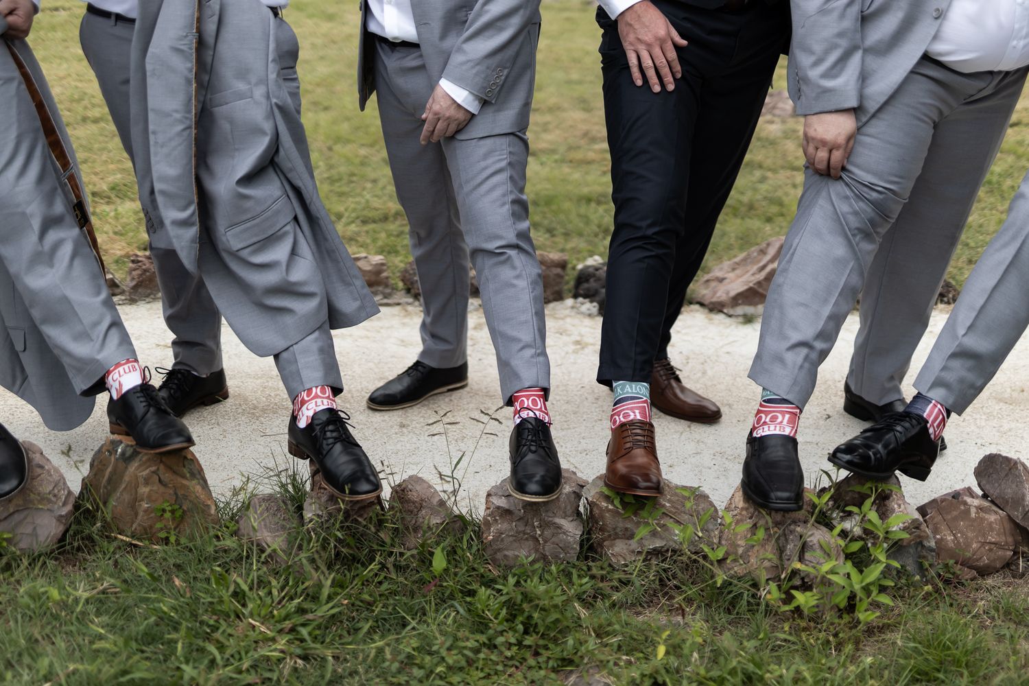 Detail shot of groomsmen showing off colorful socks while standing in a row.