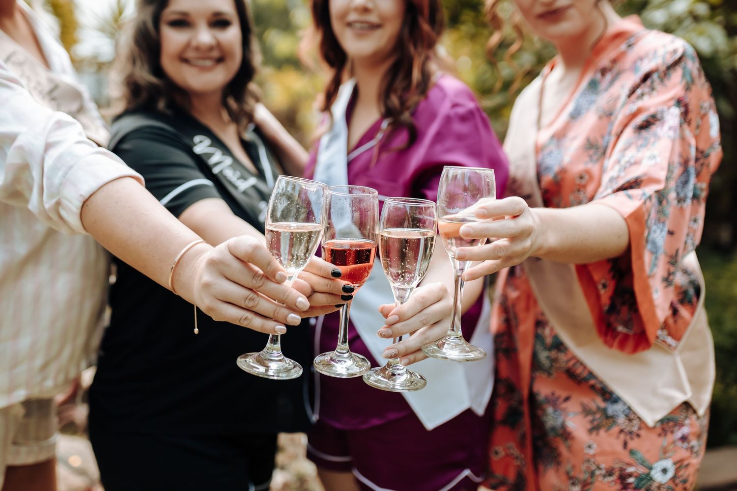 Friends clink glasses in a celebratory toast during an outdoor gathering.