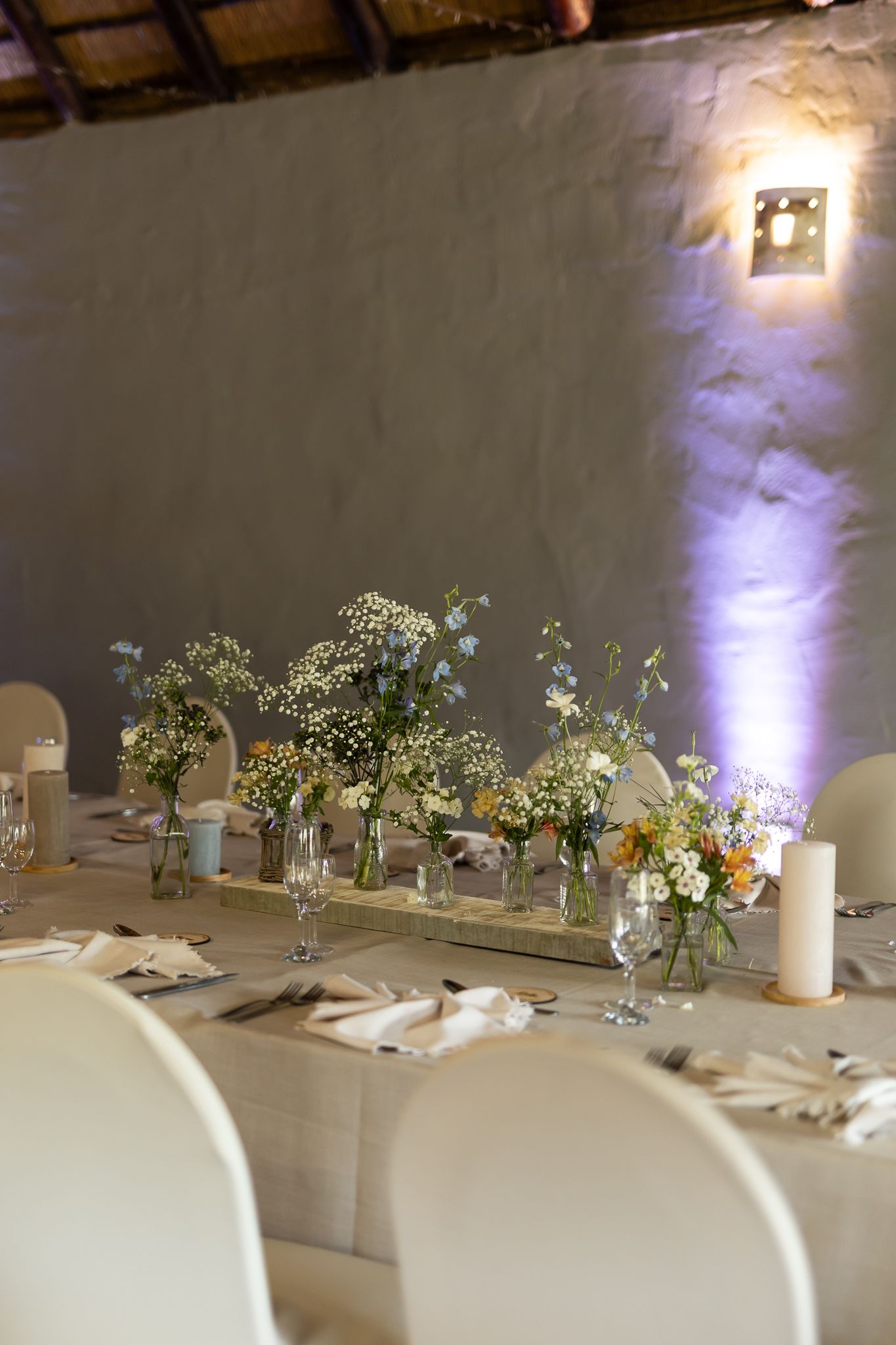 Elegant wedding table setting with white floral centerpieces and ambient purple lighting.