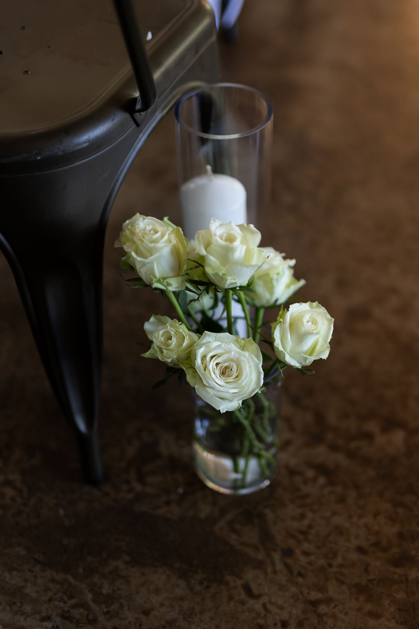 White roses arranged in a clear glass vase against a dark background.