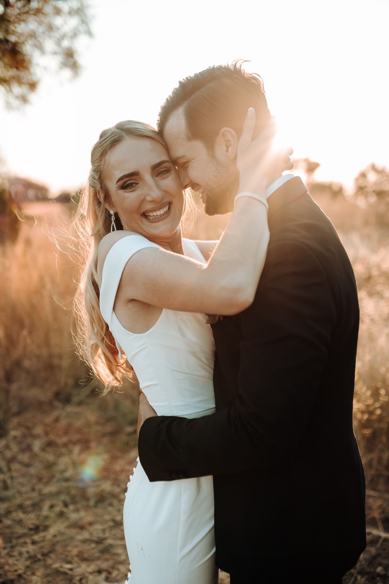 Candid wedding photo capturing a couple's laughter and joy during their golden hour portrait session.