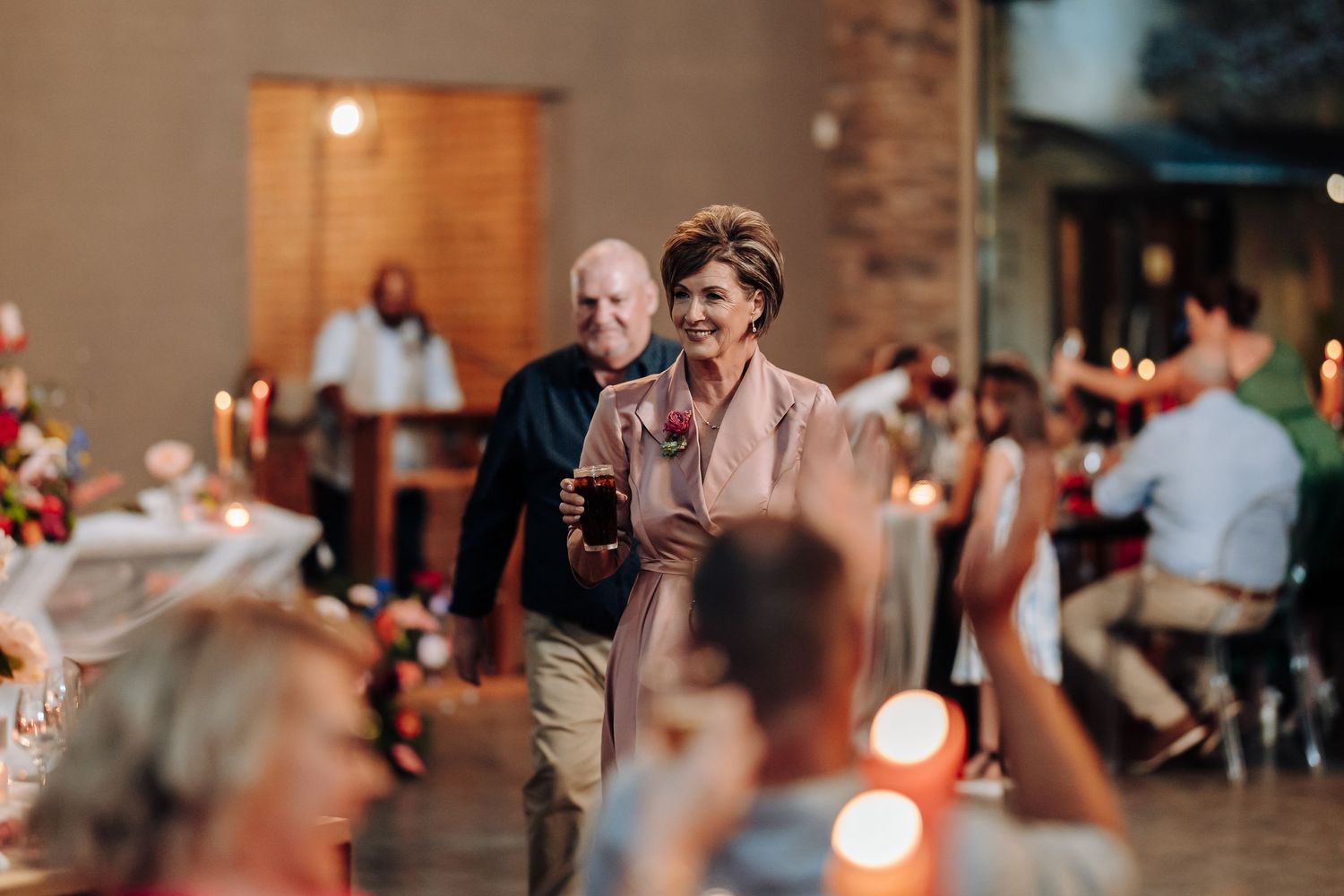 Wedding reception guests mingling and socializing in a warmly lit indoor venue.
