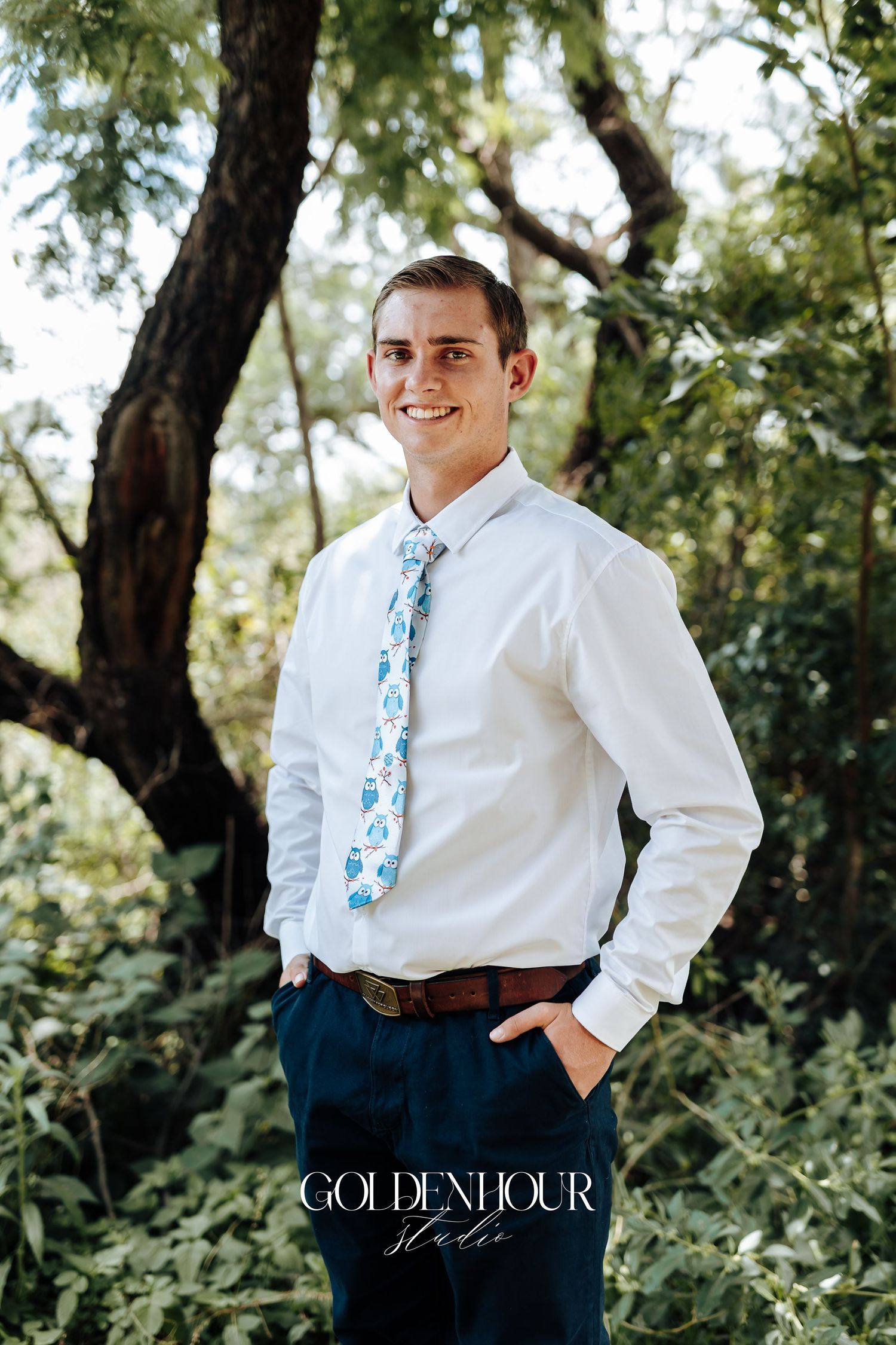 Wedding attire detail showing a white dress shirt paired with a light blue patterned tie against a natural outdoor backdrop.