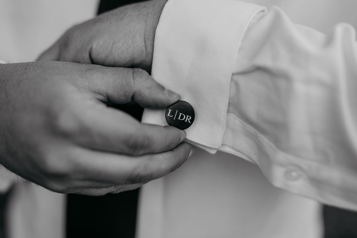 A sequence of black and white close-up shots showing hands adjusting cufflinks and formal attire.