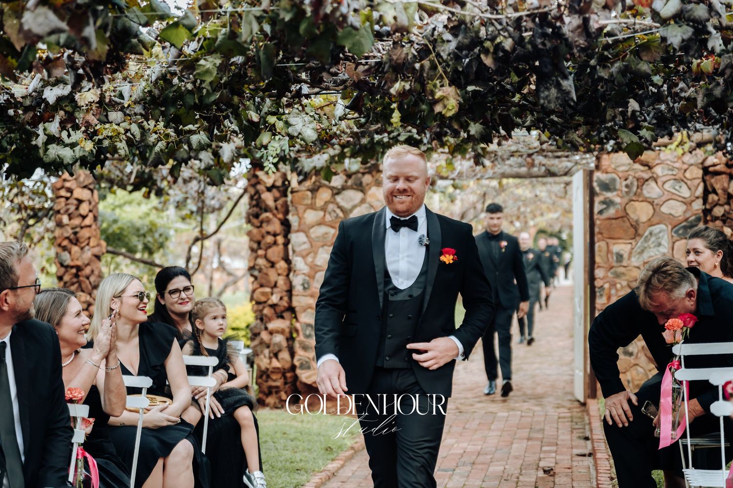 A joyful wedding celebration unfolds in a garden setting as guests mingle and dance under natural light.