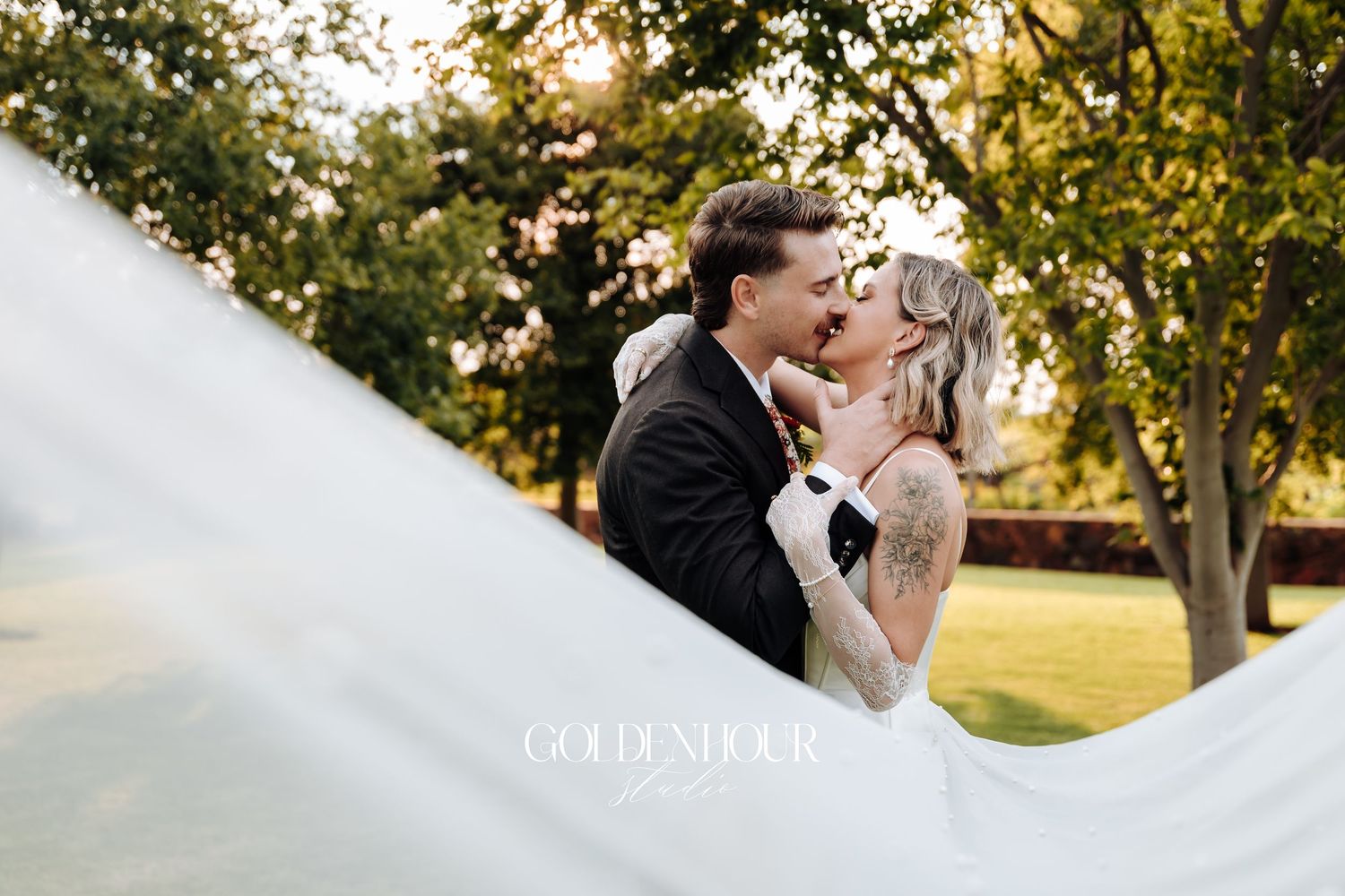 Romantic sunset wedding portrait with the bride's veil flowing dramatically in the breeze.