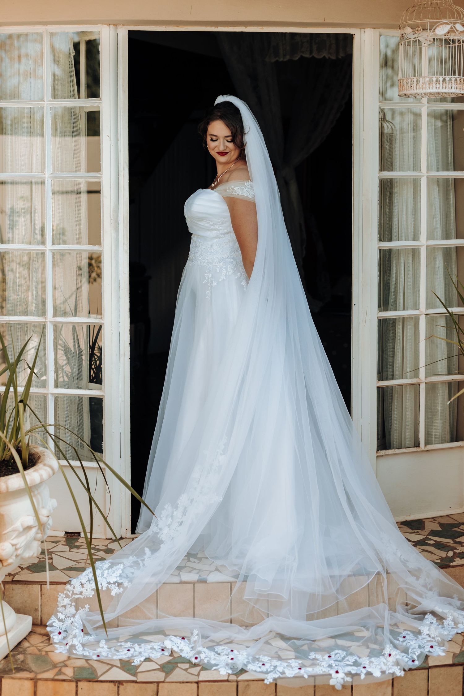 A stunning bridal portrait showing an off-shoulder gown with long cathedral veil.