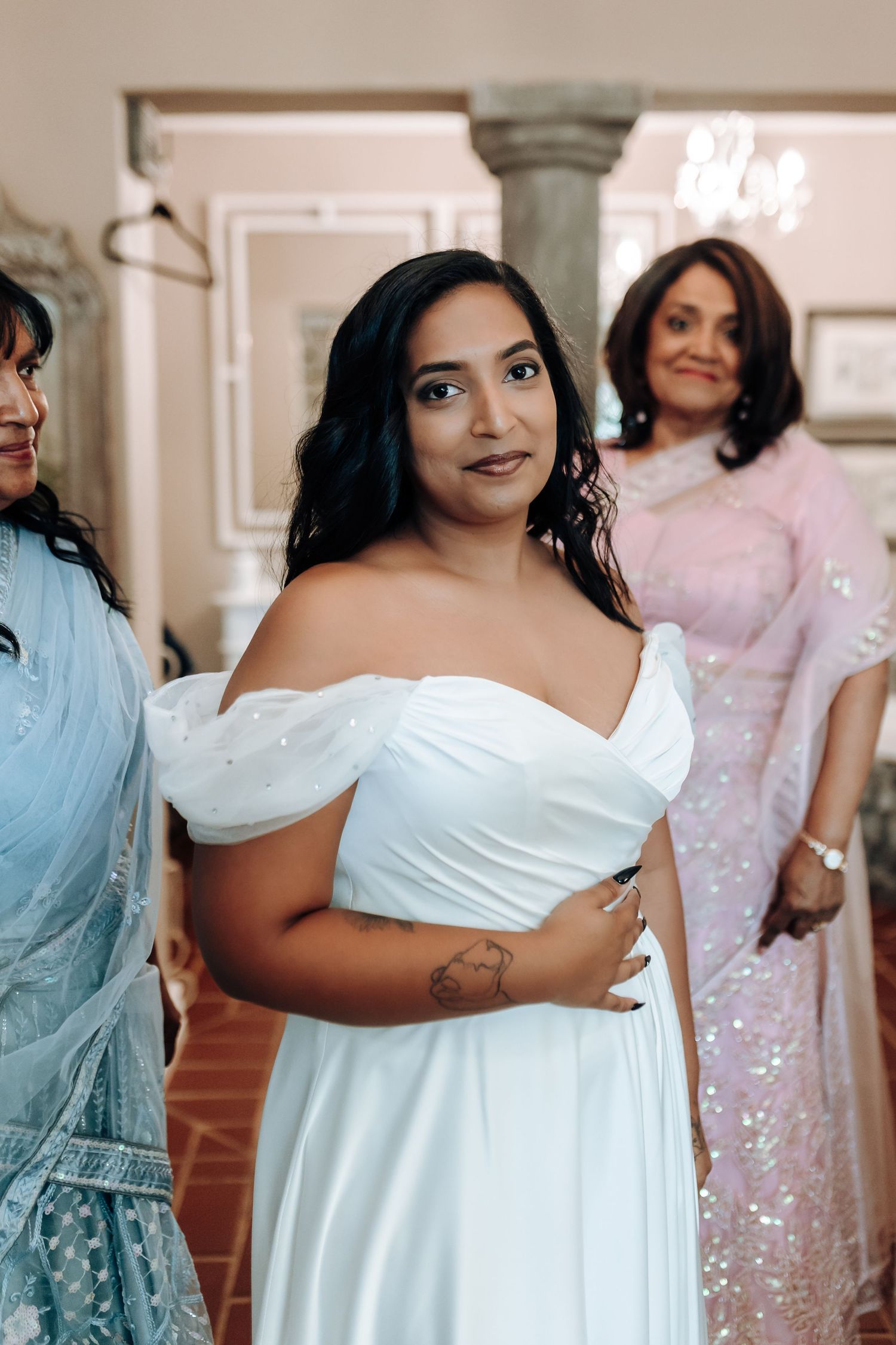 Bridal preparation moment in elegant room with ornate mirrors and classical architecture.