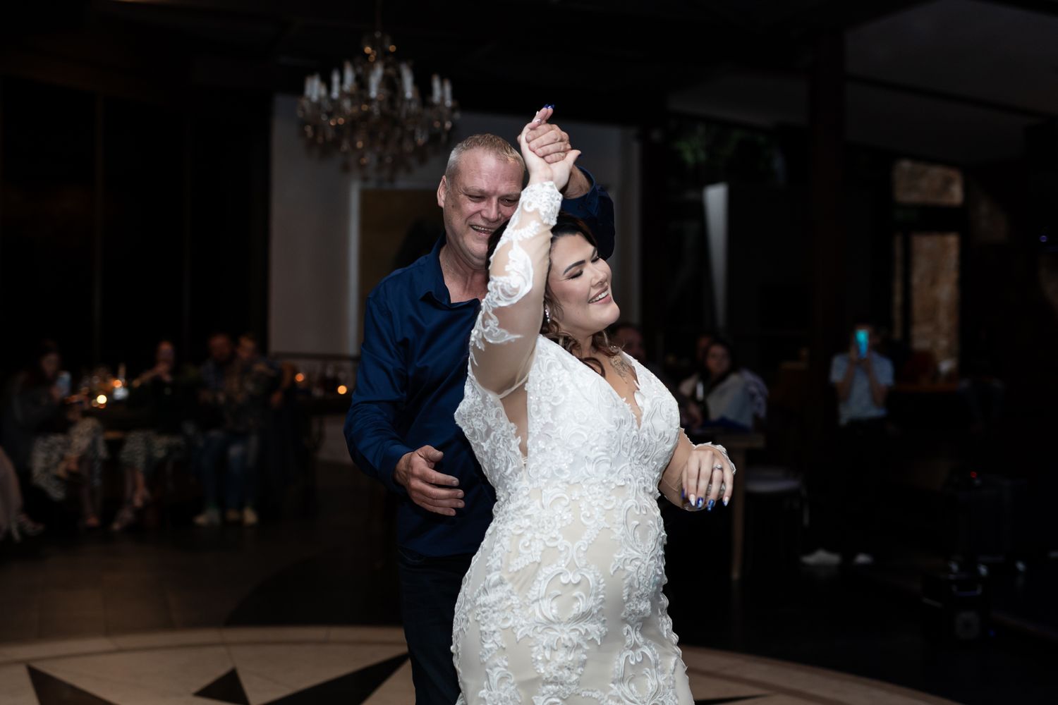 Couple performs romantic dance move during their wedding reception in an elegant ballroom.