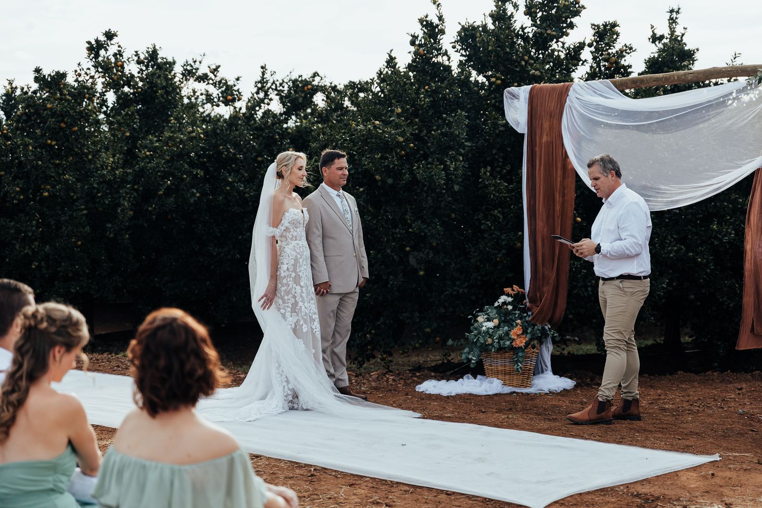 Wedding ceremony in progress with couple and officiant at rustic outdoor altar.