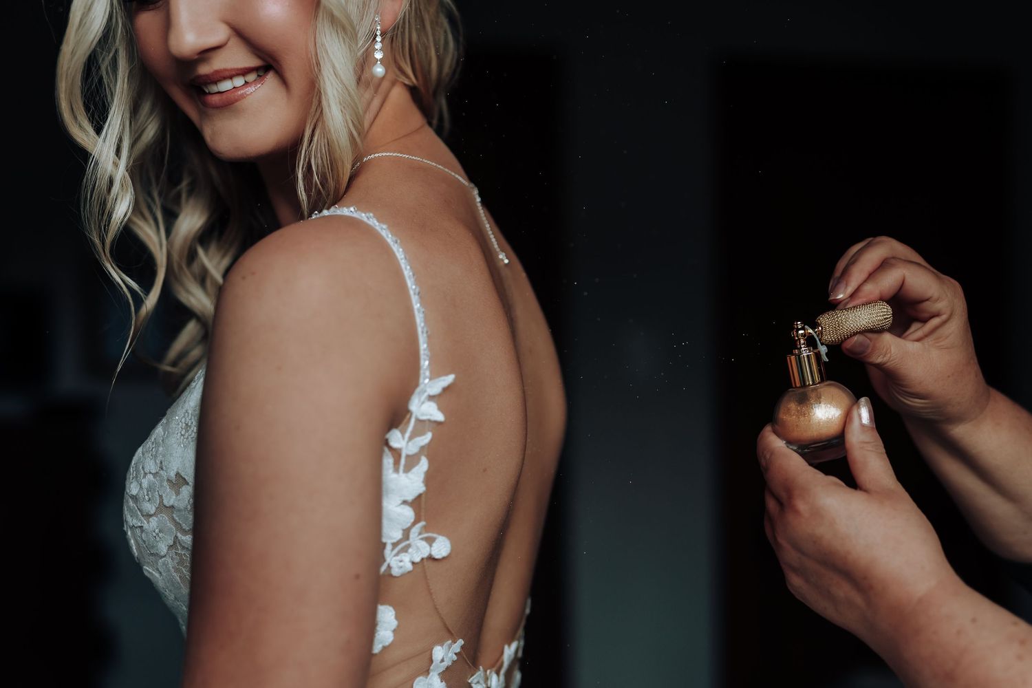 A bride gets ready on her wedding day wearing delicate lace straps and sparkling earrings.