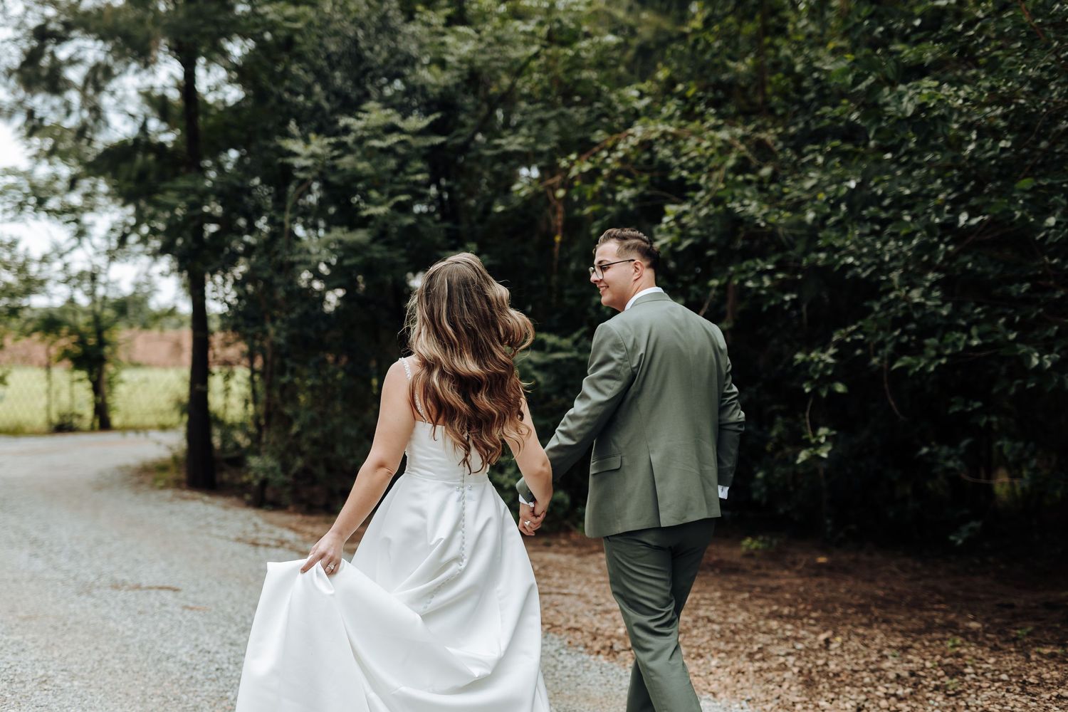 A couple in wedding attire walks hand in hand through a lush garden path during their romantic outdoor photo session.