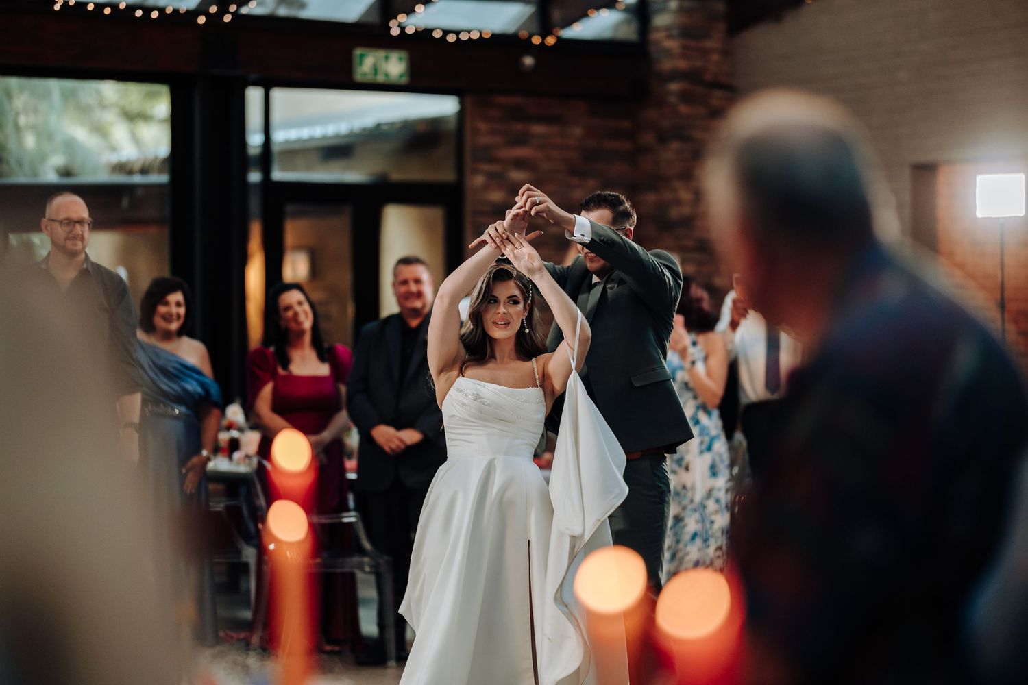 Wedding reception guests dancing and celebrating on a dimly lit dance floor with glowing orange lights.