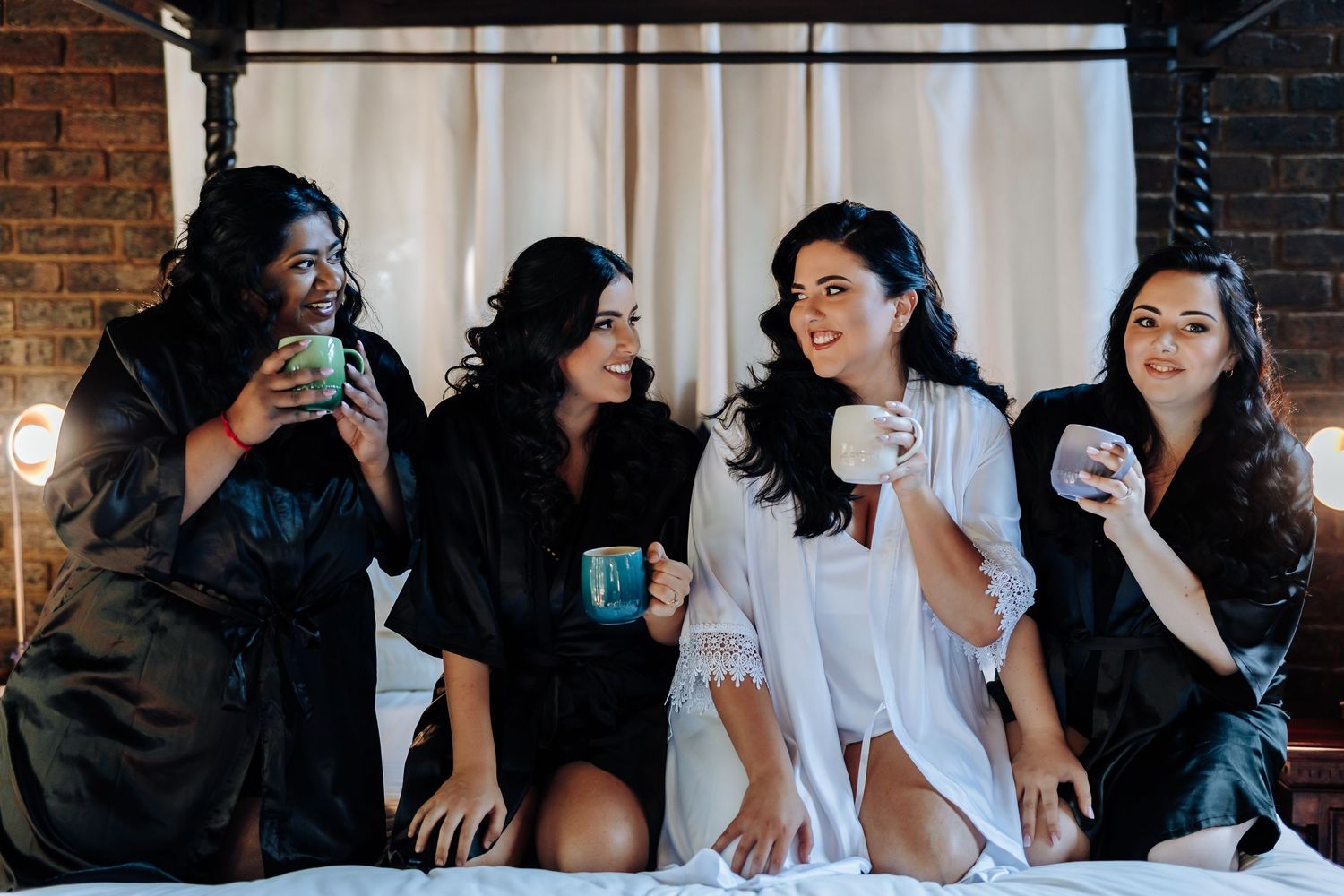 Wedding party getting ready in a rustic brick-walled room with natural lighting.