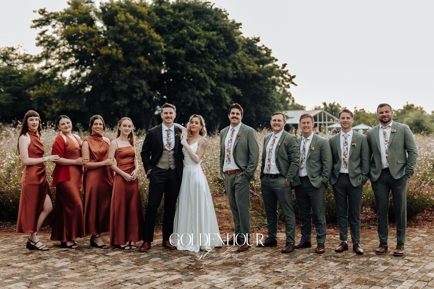 Wedding party in burgundy dresses and gray suits posed outdoors.