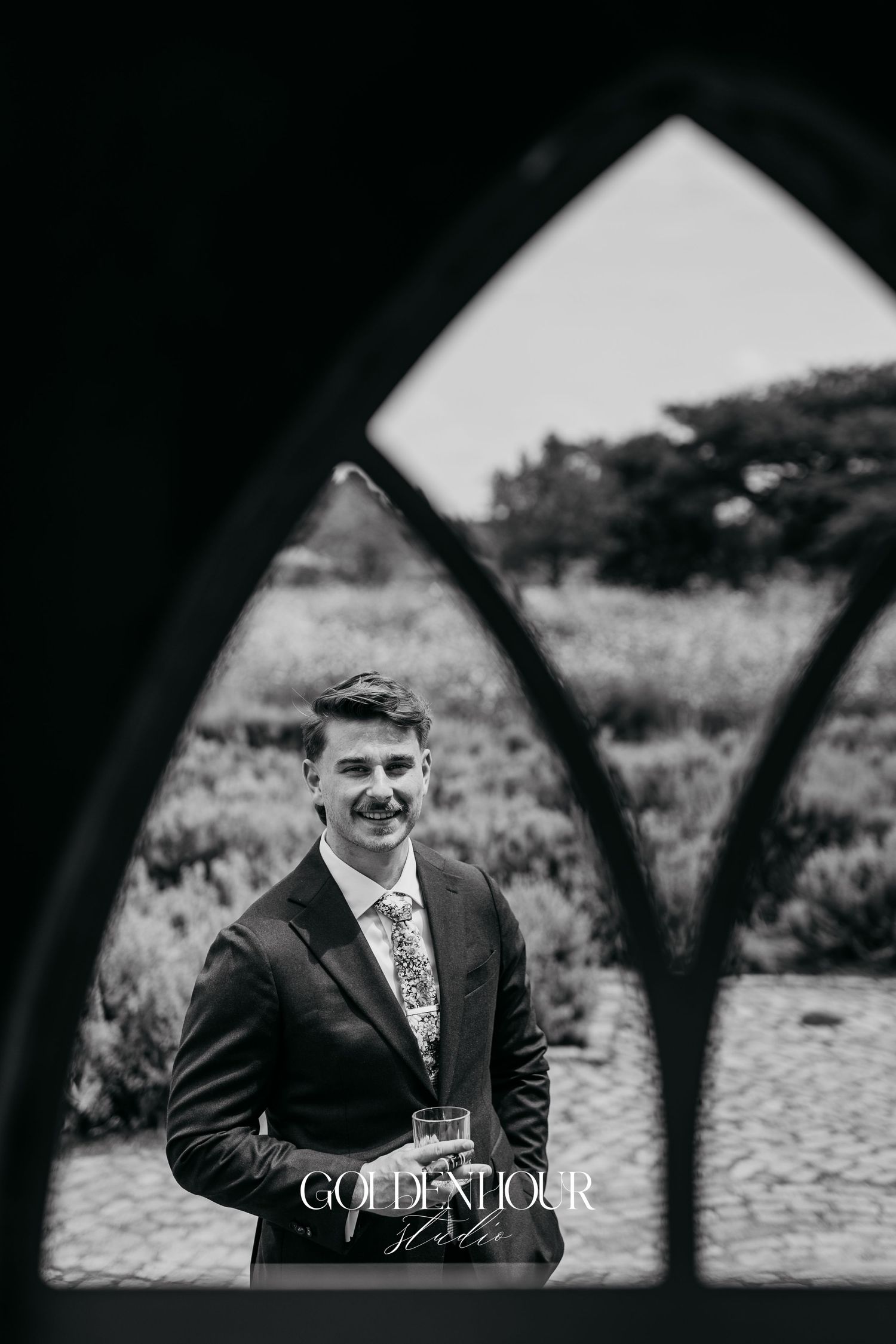 Black and white wedding portraits framed through an architectural arch.