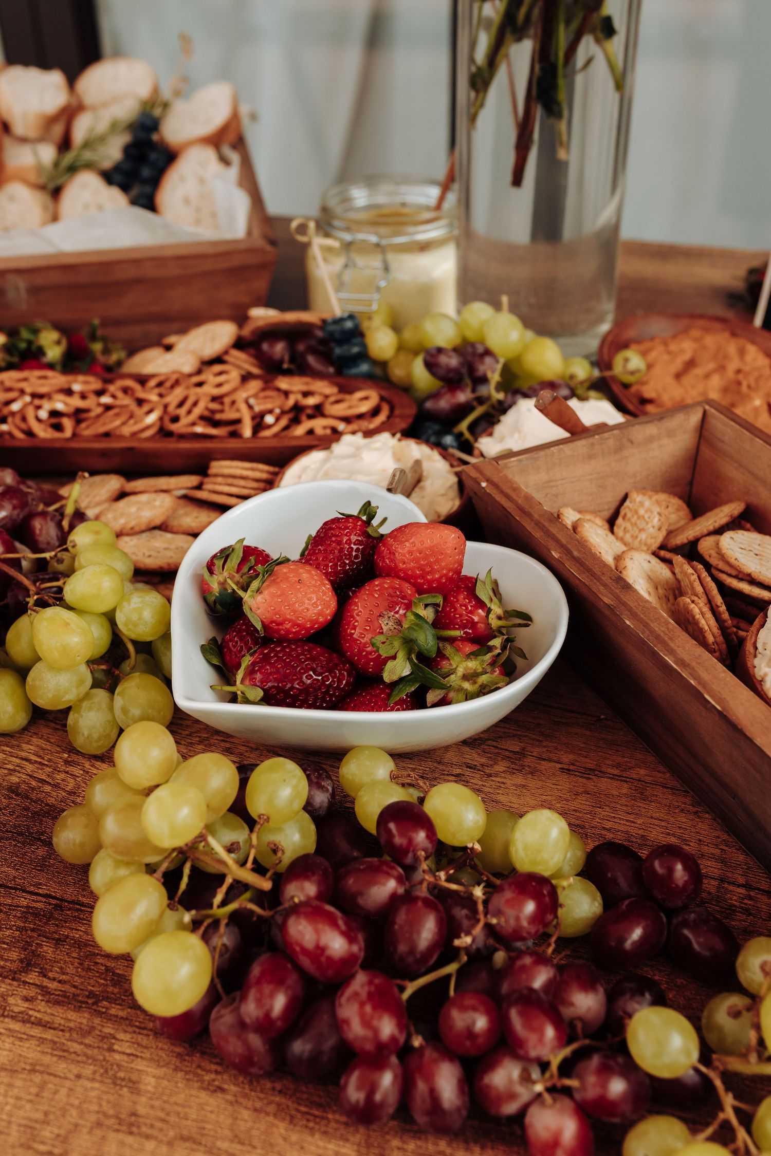 Fresh red and green grapes with strawberries arranged on rustic wooden serving boards create an appetizing fruit spread.