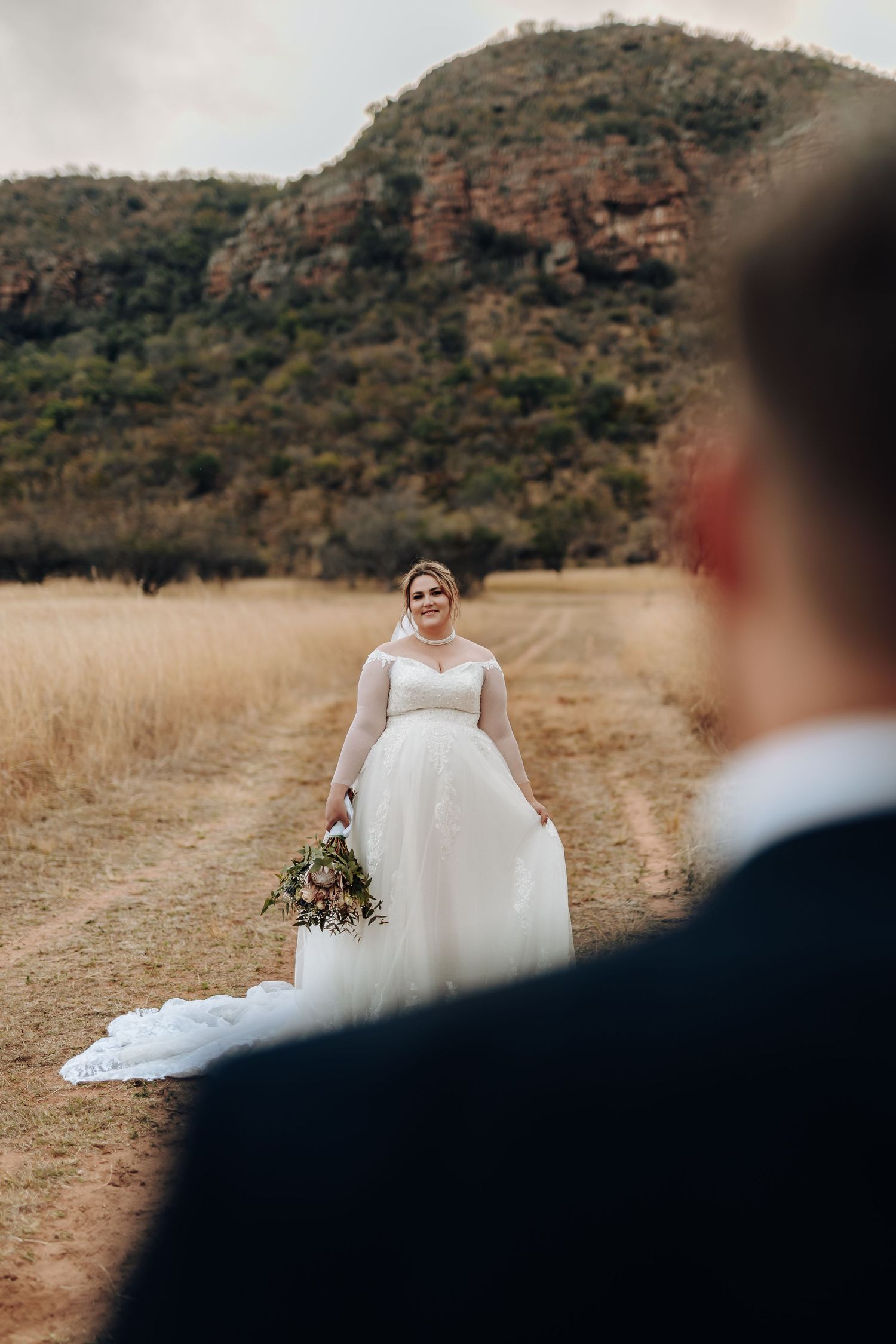 Stunning desert mountain landscape wedding portrait session with couple in elegant white dress against rugged terrain.