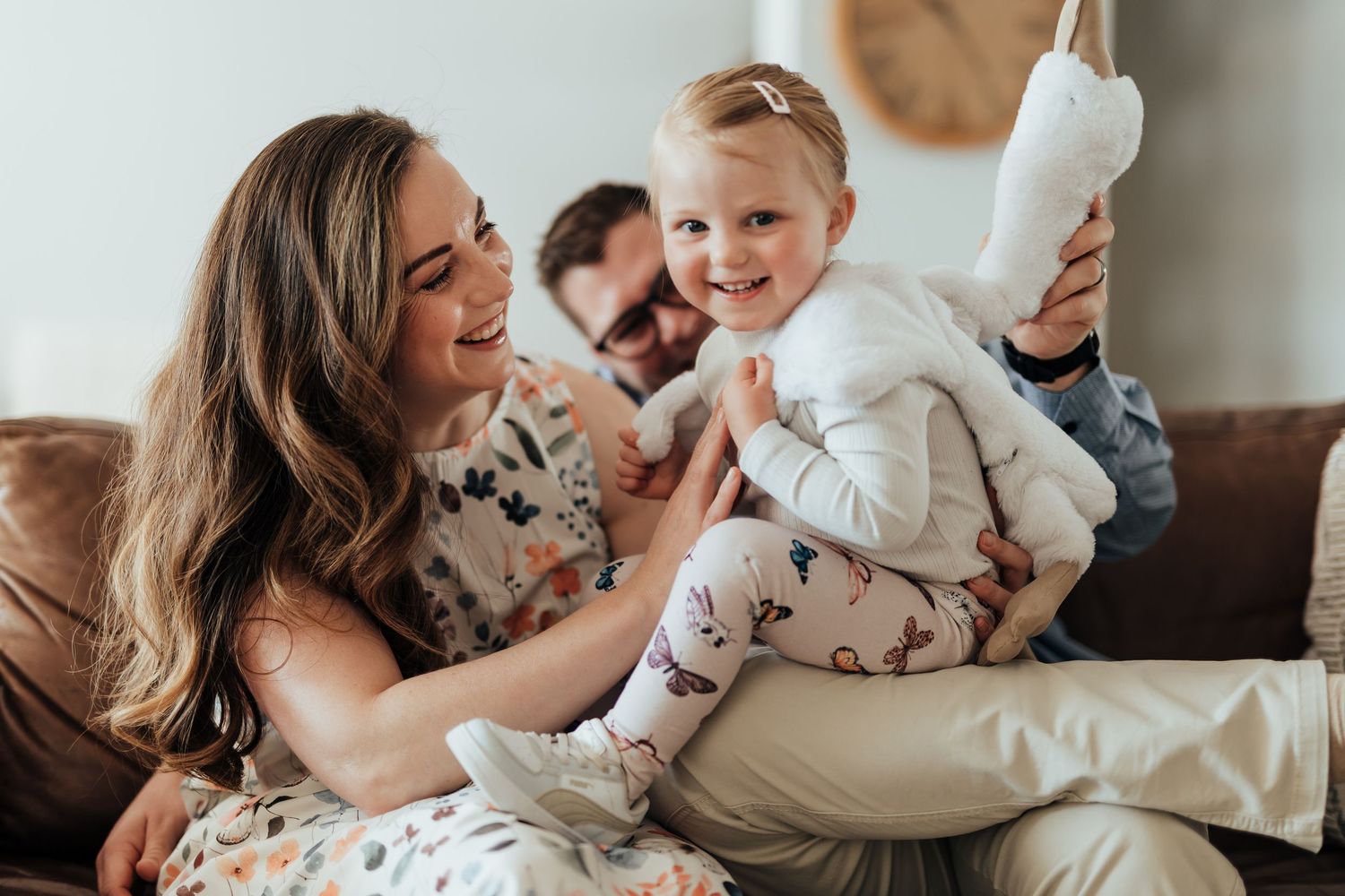 A loving family shares tender moments together while lying in bed on a bright morning.
