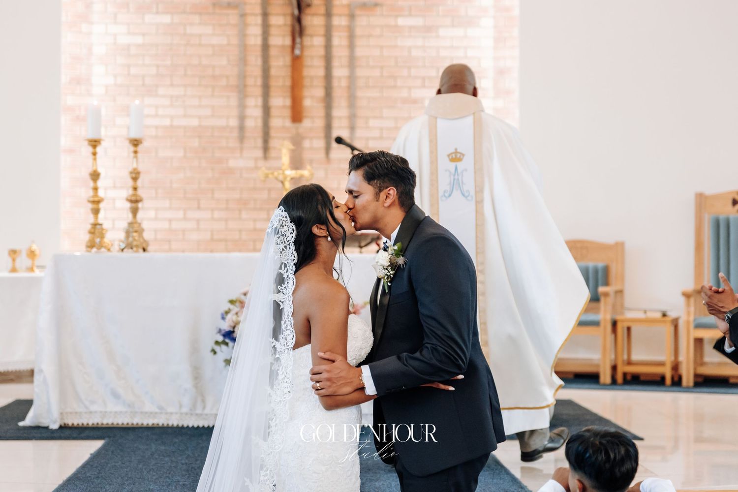 Catholic wedding ceremony taking place in a traditional brick church setting.