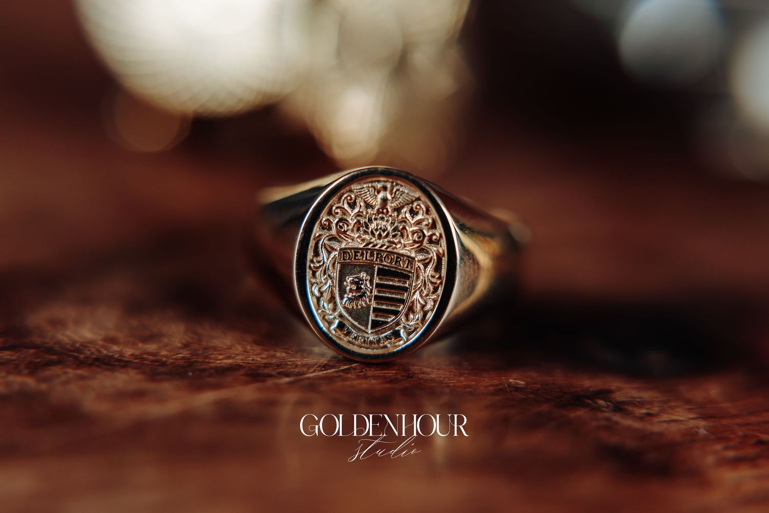 A macro close-up shot of a vintage style signet ring with a family crest design on a textured brown surface.