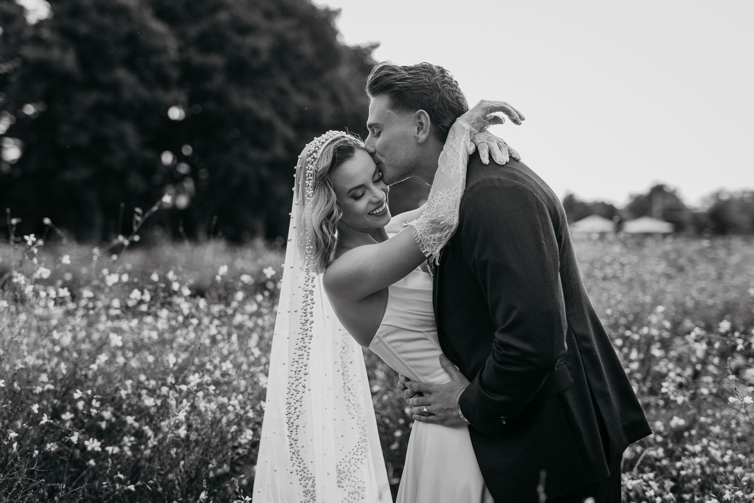 A romantic black and white photo series of a couple embracing in a wildflower meadow on their wedding day.